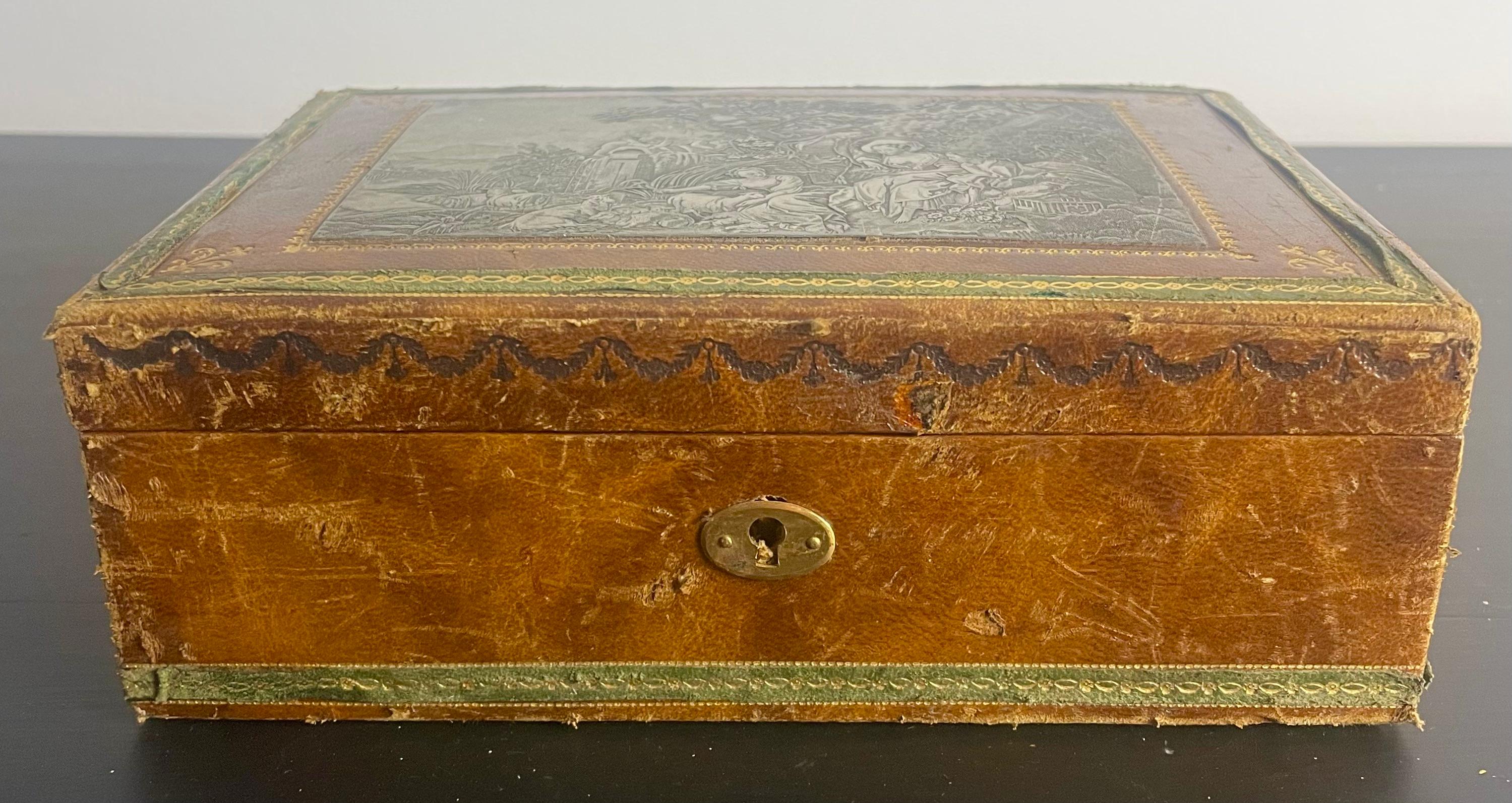 Charming wooden jewelry or sewing box covered in brown leather, surrounded by a dark brown inlaid frieze and a decorative green frieze glued around the box.
The leather is decorated with golden patterns on small irons.
The inside of the box is made