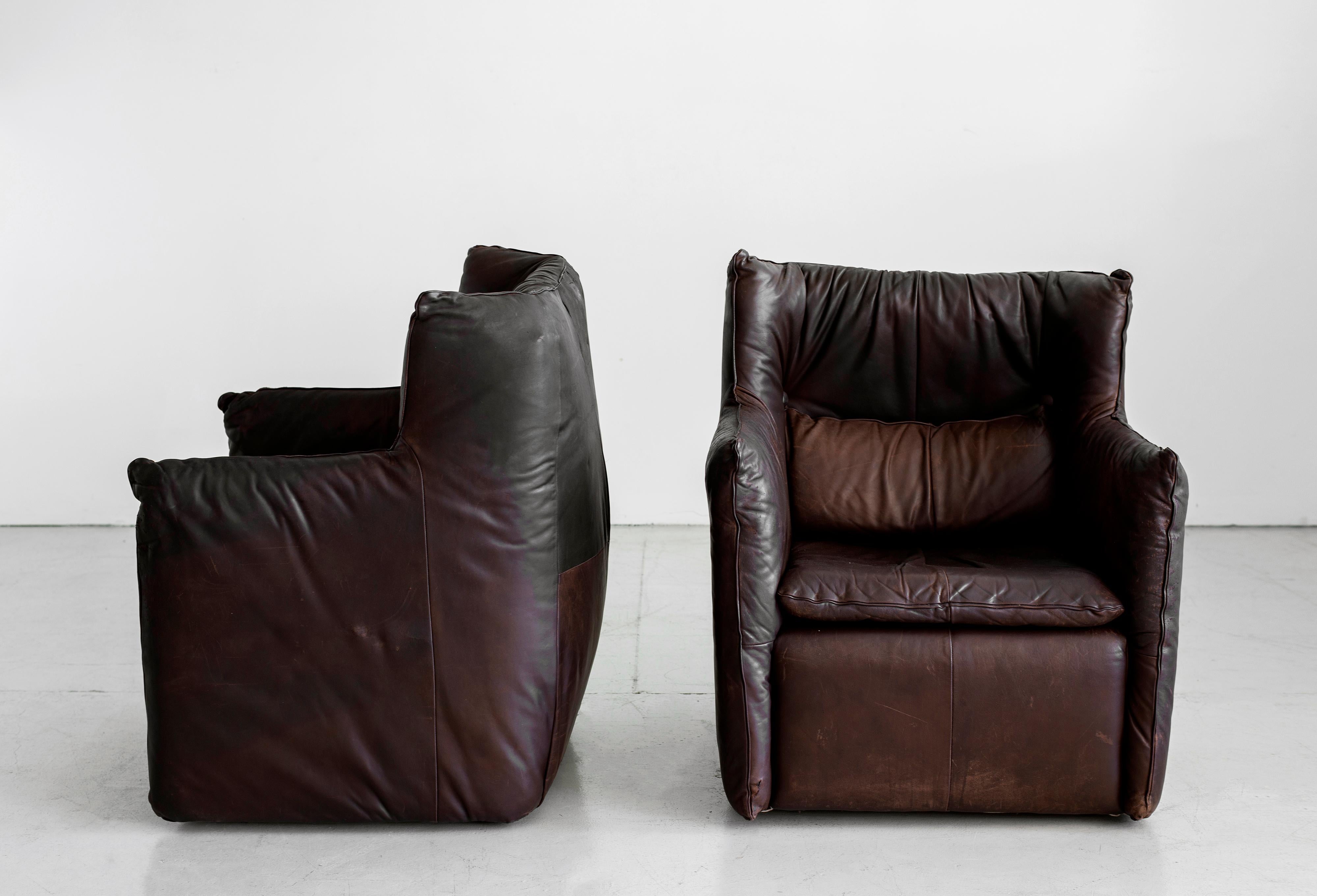 Great pair of leather lounge chairs by Gerard Van Den Berg. Original chocolate brown leather upholstery. Removable lower lumbar pillow attached with button and loop detail. Supple leather has beautiful age and patina with some small pinhole cracks.