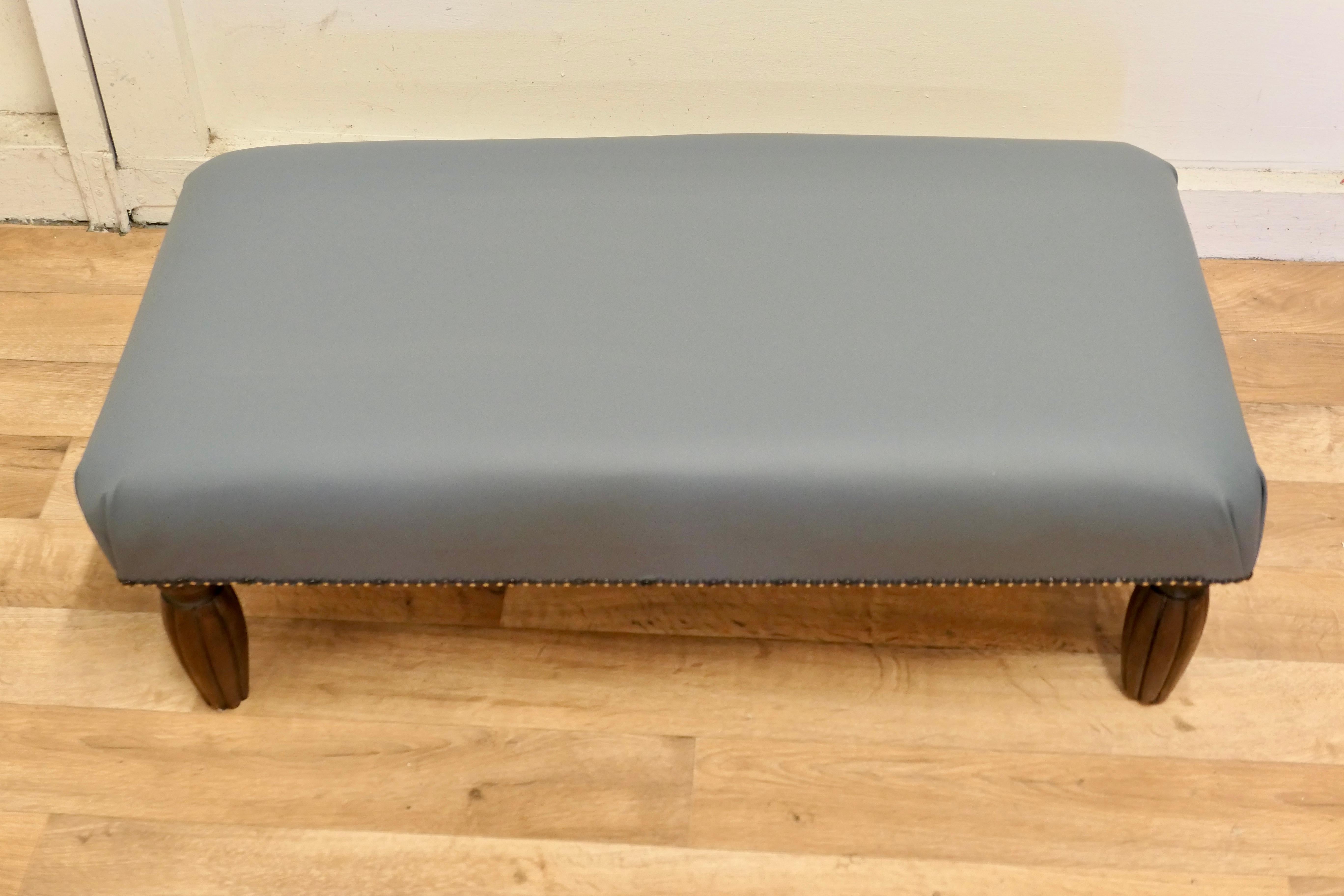 French leather upholstered long foot stool 

A Lovely piece standing on fluted shaped legs and the 5” deep seat is upholstered in beautifully soft “Mercedes Blue/Grey” leather with brass studs
Measures: The stool is 12” high, 35” long and 18”