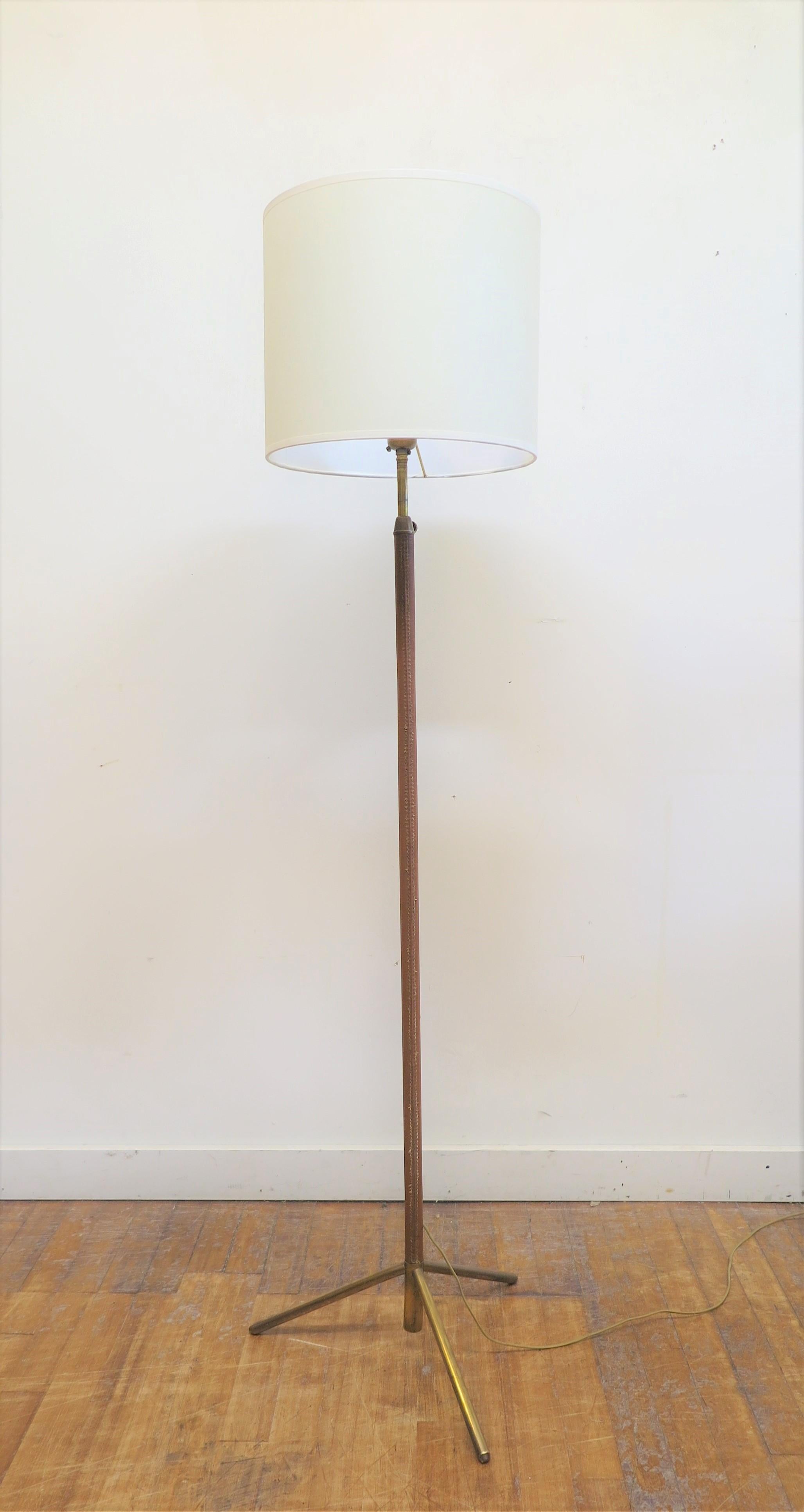 Lampadaire à rallonge du milieu du siècle dernier en cuir, attribué à Jacques Adnet. Lampe de sol en cuir français boîte cousue marron clair cuir et couture d'origine. Base tripode en laiton massif. La lampe s'étend jusqu'à 74 pouces à partir de 56