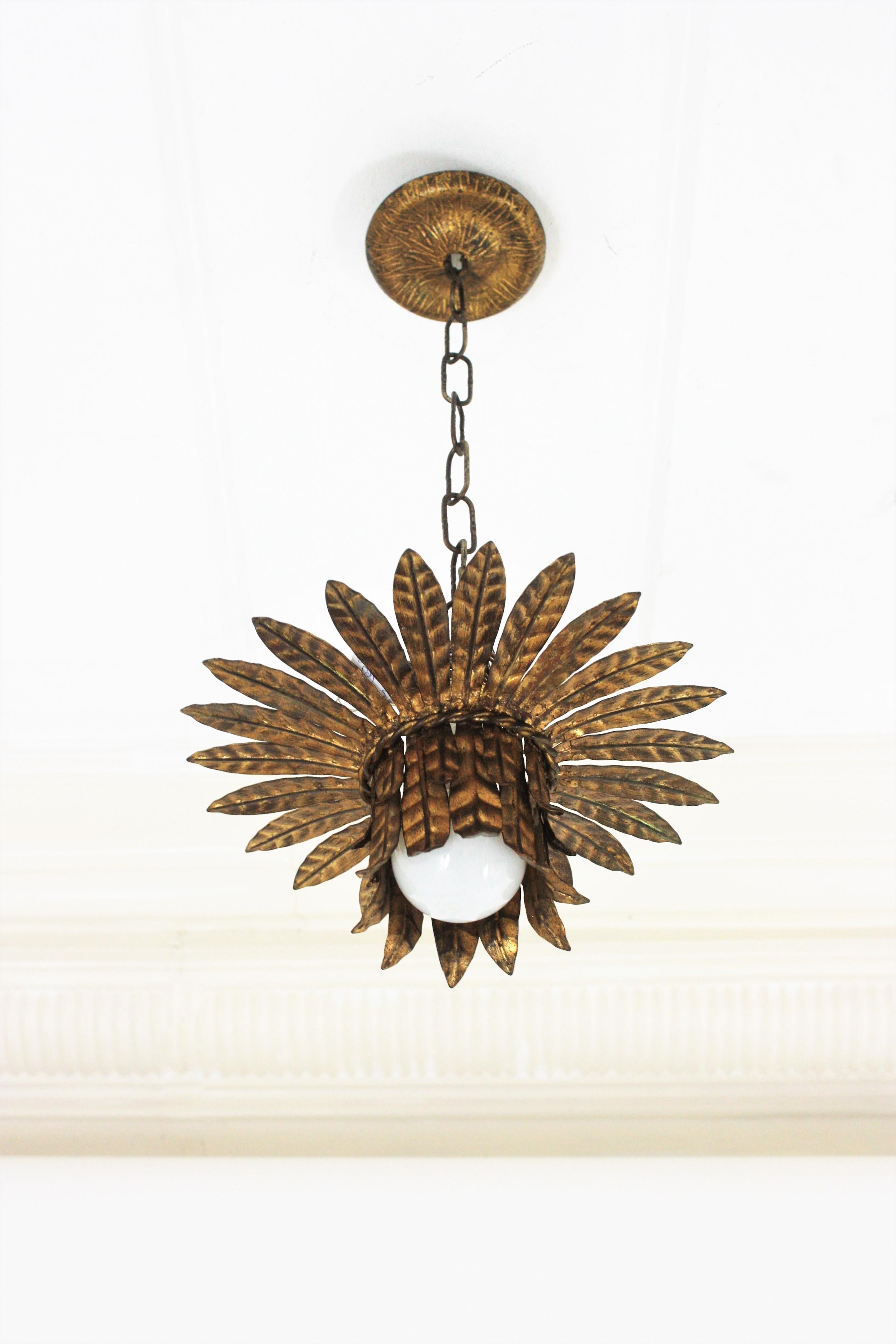 Hollywood Regency gilt iron leaves bouquet crown flush mount / pendant. France, 1940s.
This flush mount features a bouquet of iron leaves distributed as a crown sunburst and adorned with a twisted iron rope. It has one central light. The leaves show