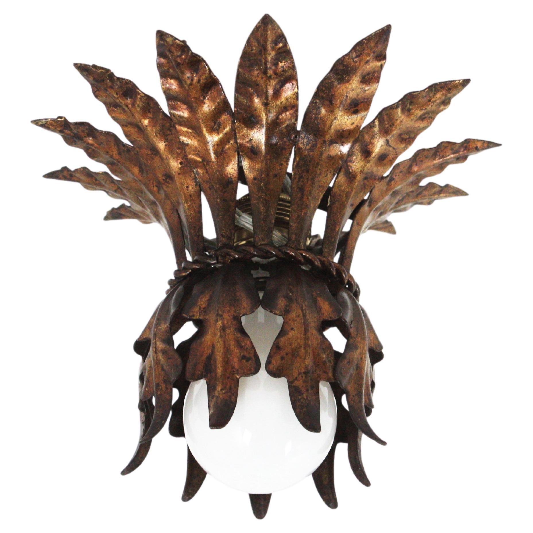 Hollywood Regency gilt iron leaves bouquet crown flush mount / pendant. France, 1940s.
This flush mount features a bouquet of iron leaves distributed as a crown sunburst and adorned with a twisted iron rope. It has one central light. The leaves