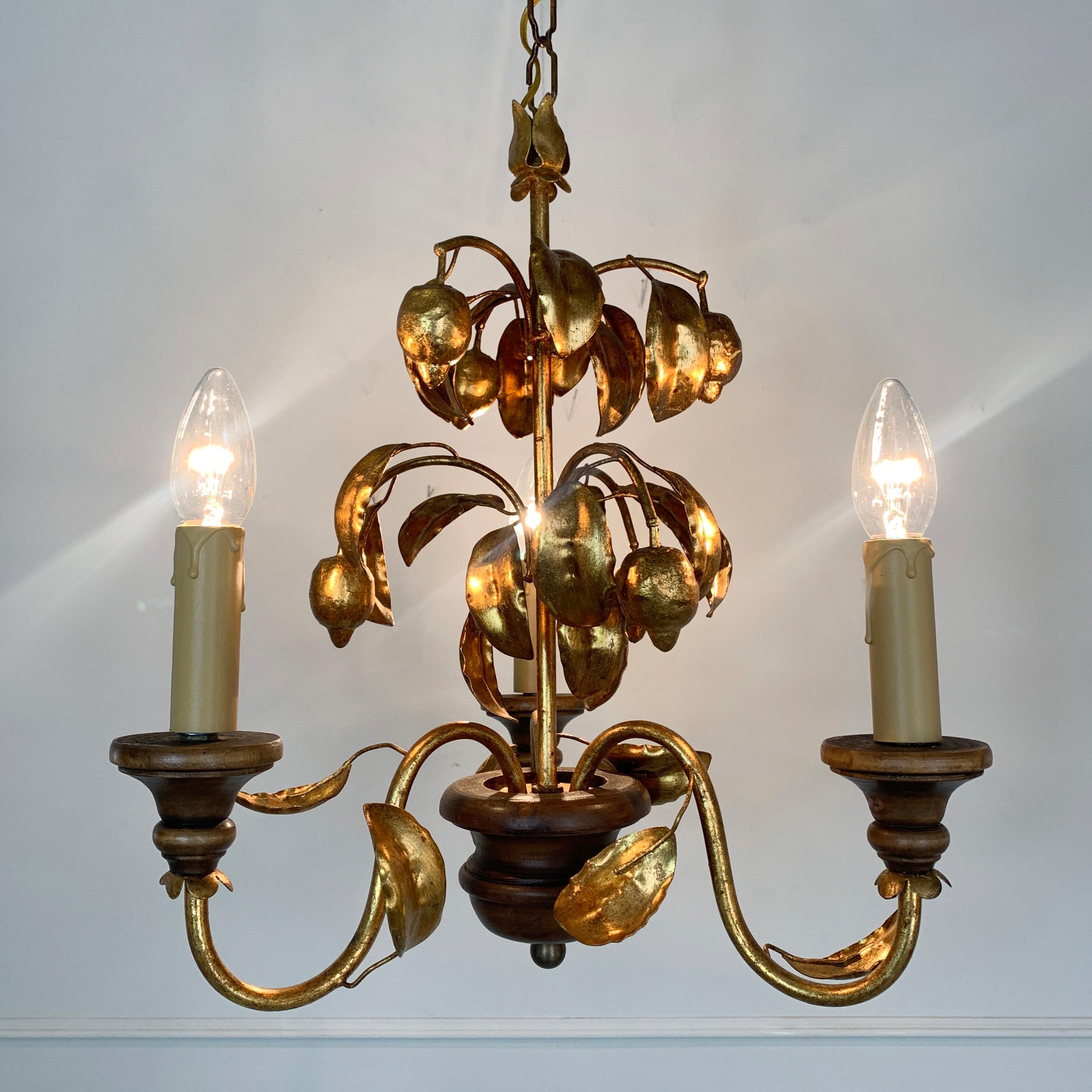 Gilt lemons and leaves toleware chandelier
circa 1970s, France
Fabulous bright original gold leaf finish
3-arm chandelier with turned wooden finial and lamp holder cups
Measures: 70cm total height, 37cm width, 13cm ceiling rose width
 
The light is