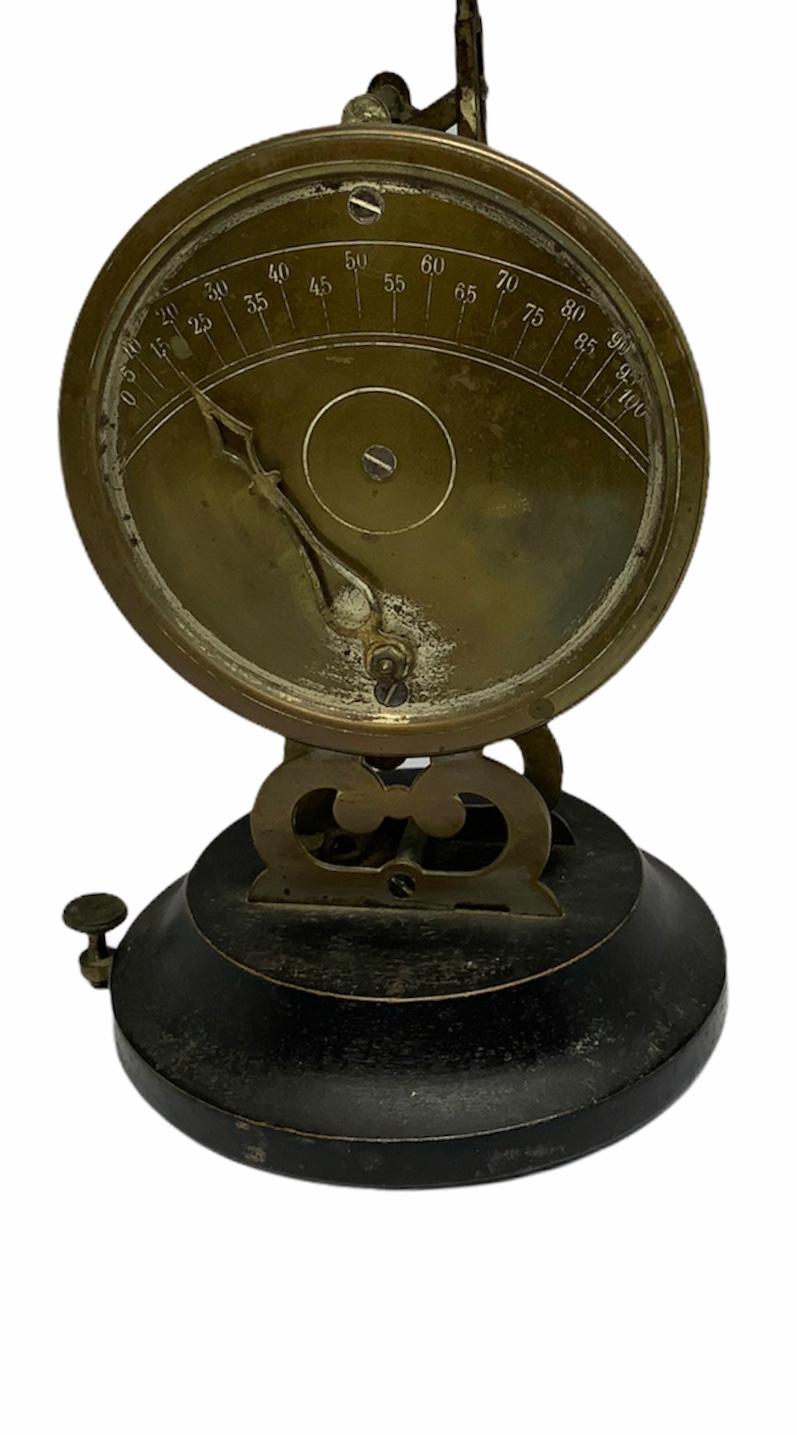This post office scale with graduated round plate consist of a round flat dish and a pendulum counterweight on a wood base. There is a screw in the right side of the base that is used to level the scale. Also two legs ending as double C-scrolls