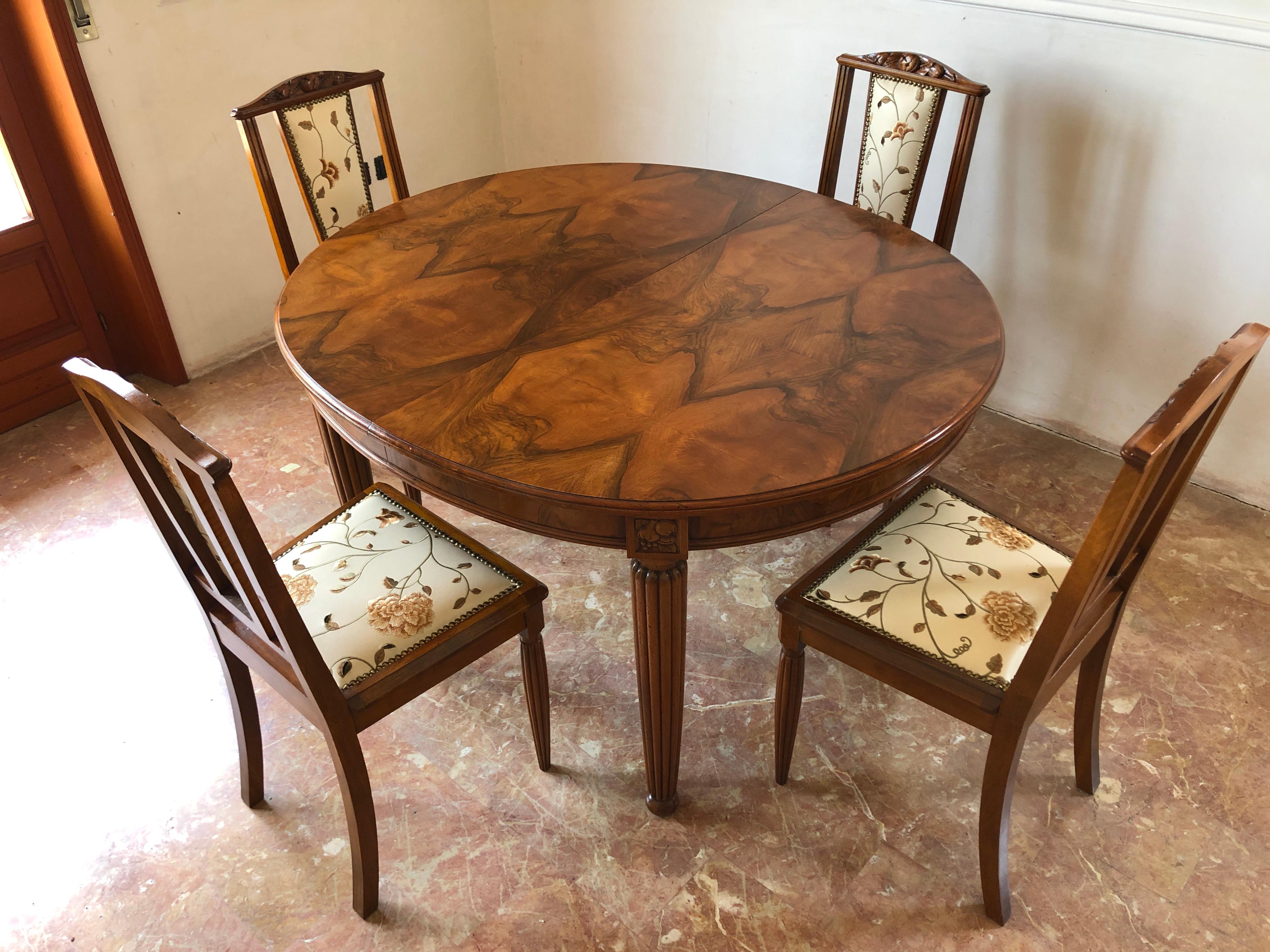 French liberty Art Nouveau dining set composed by a dining table in a very valuable walnut feather, grooved legs with naturalistic motif, characteristic elements of the period and six beautiful chairs with decorative inlays on the backs, grooved
