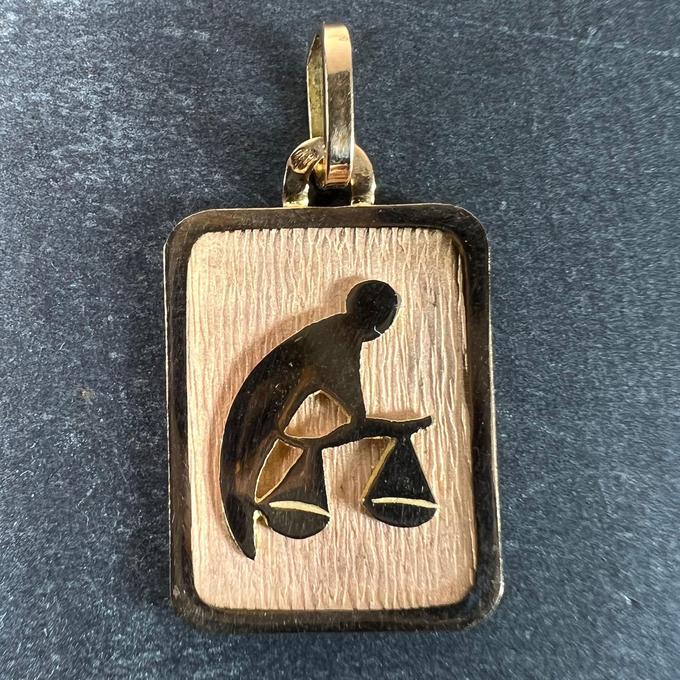 Pendentif de charme français en or jaune 18 carats (18K) conçu comme une médaille rectangulaire avec un renfoncement gravé représentant une personne portant une paire de balances représentant le signe astrologique zodiacal de la Balance. Estampillé