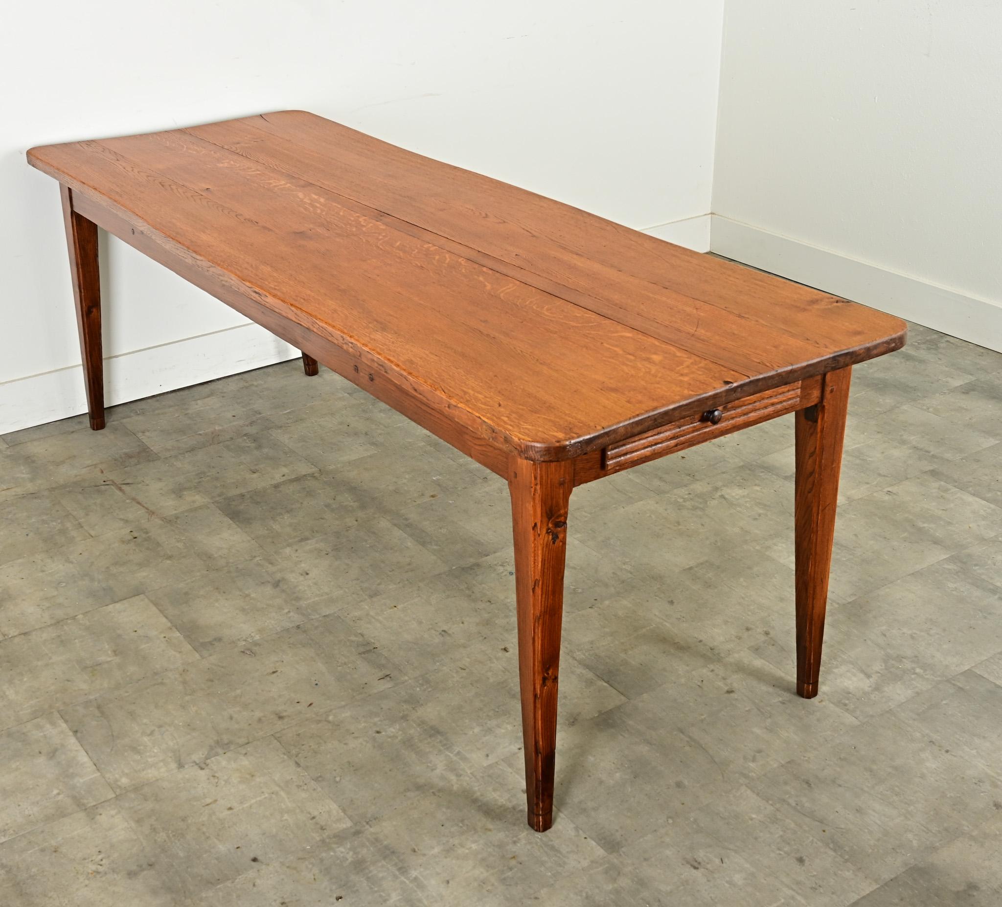 Une table de ferme française très créative et inspirante, datant d'environ 1910, fabriquée à la main en chêne clair. La surface supérieure, composée de planches sciées sur quartier avec un motif de grain fantastique, présente un bord légèrement