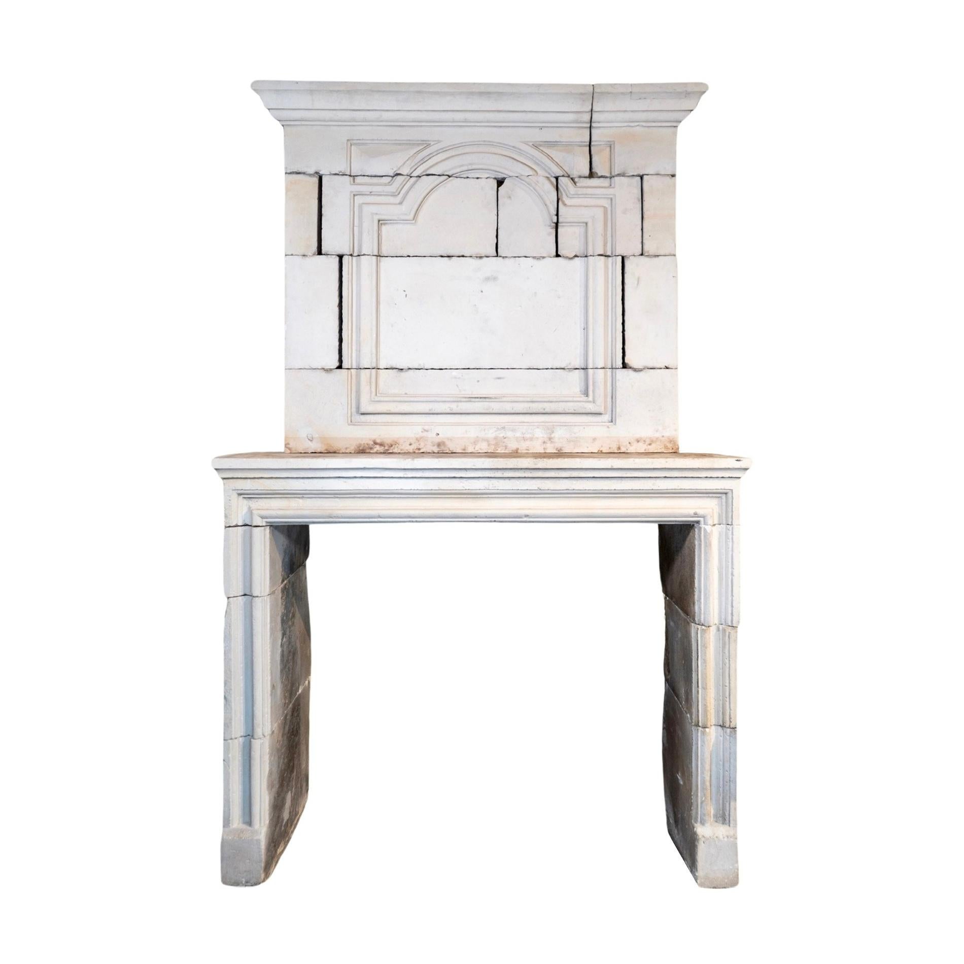 This antique French Limestone Fireplace is a stunning addition to any home. Handcrafted in France in 1810, it features a carved trumeau and intricate style carvings, making it a true work of art. With semi-quatrefoil designs and a Louis XIV style