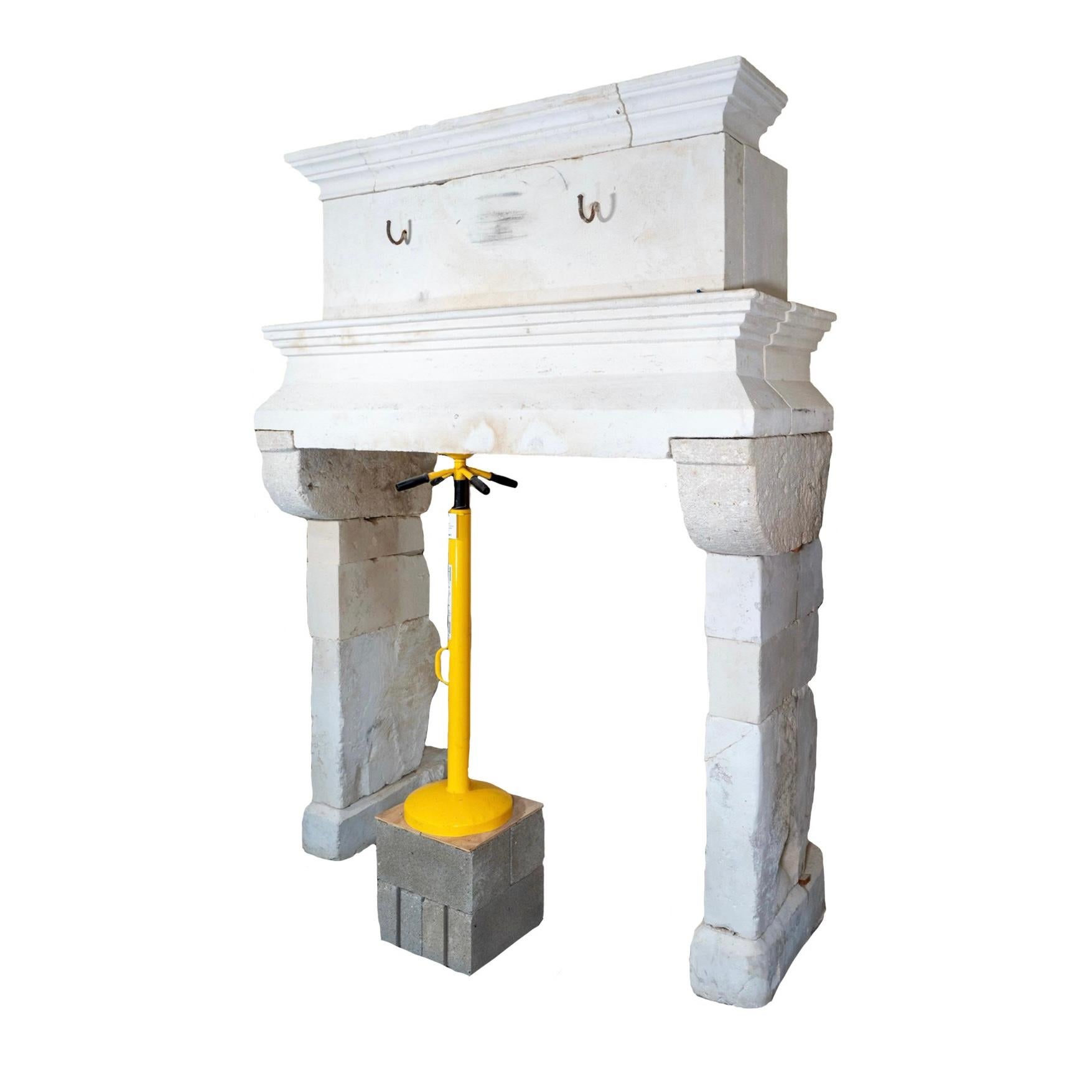This antique French Limestone Fireplace Mantel dates back to the 1680s and has been reclaimed for modern use. Featuring iron hooks at the center of the mantel top for hanging pots and pans, this mantel is a historical piece that adds both beauty and