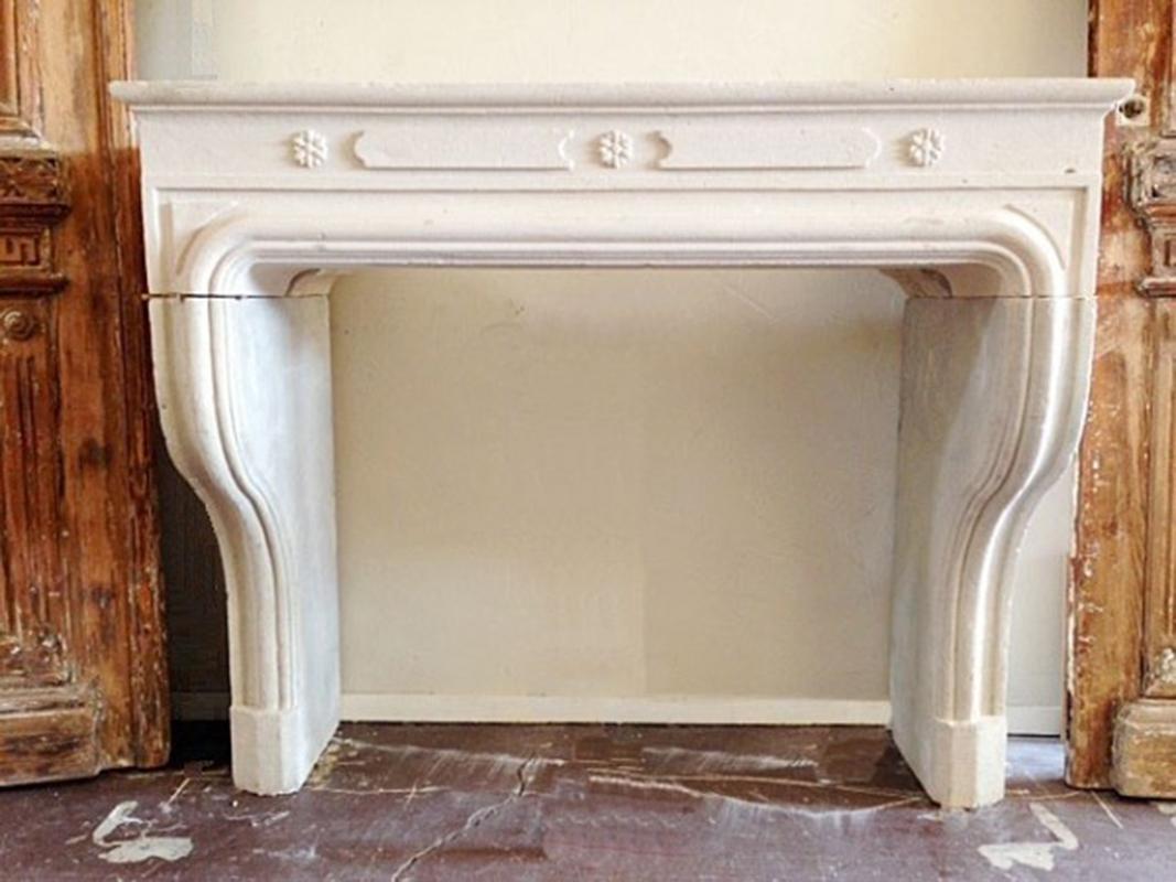 Charming contemporary mantel hand carved in France in a very light native limestone. The up-dated motifs will fit seamlessly into a variety of design plans. Two-part rounded molding outlines the firebox opening and continues down the gracefully