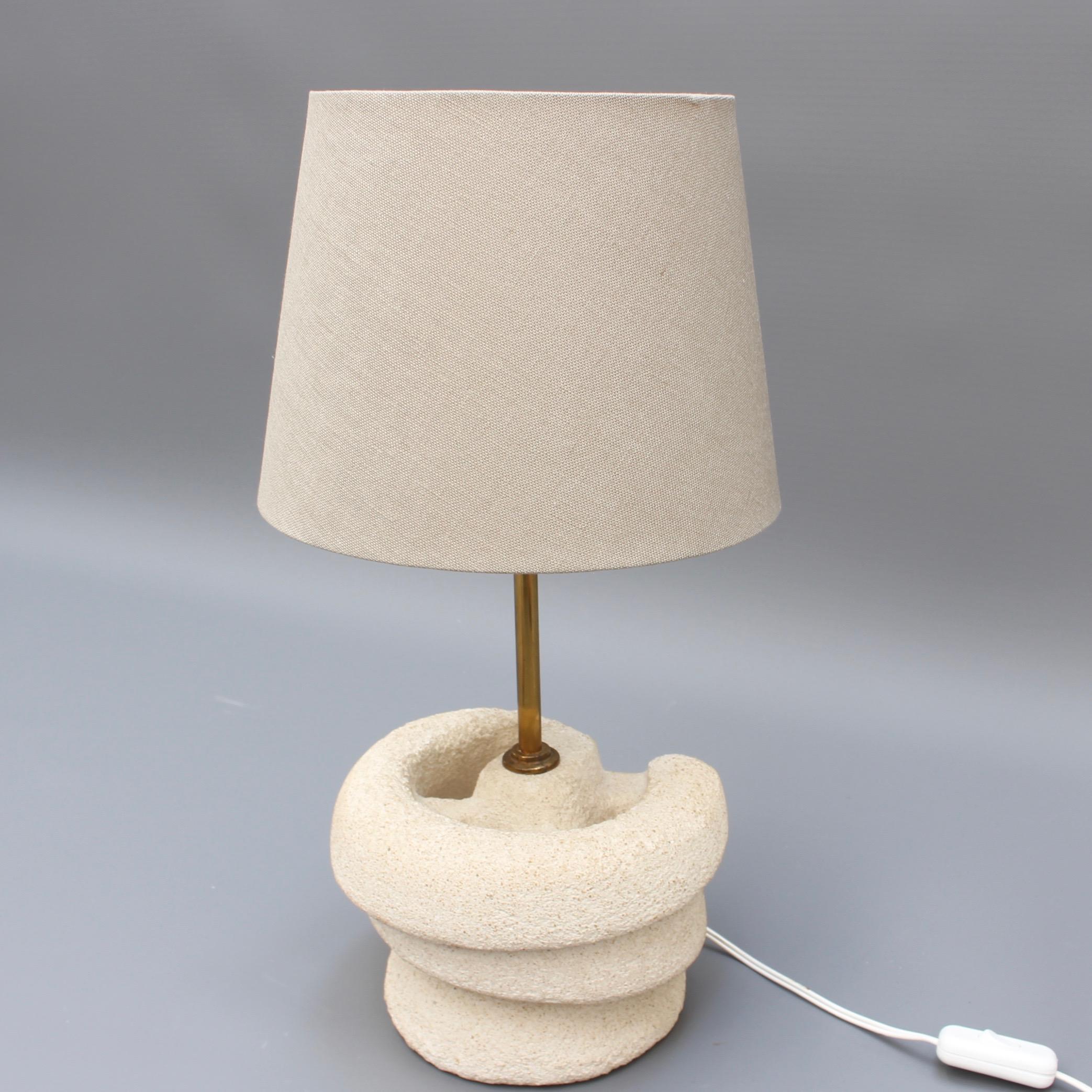Stylish French beige limestone (pierre du Gard) table lamp (circa 1970s) with modern, spiralling structural frame and brass vertical shade support. Visually inspiring and very substantial and tactile. Its neutral colour is perfect for modern living.