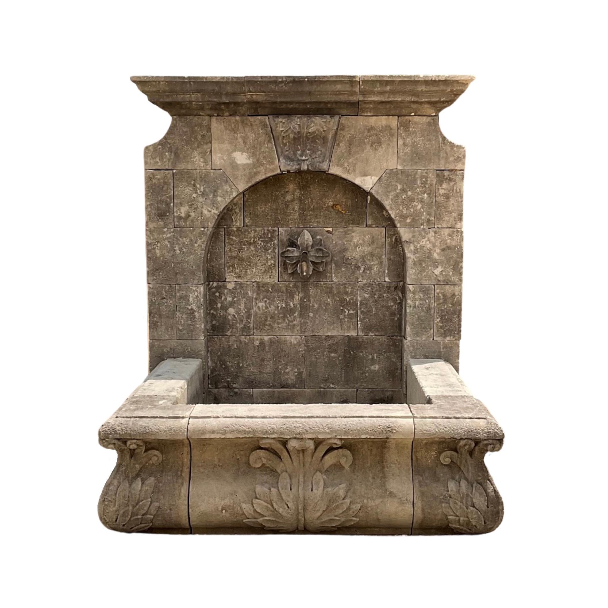 Dieser prächtige Wandbrunnen aus französischem Kalkstein ist eine perfekte Ergänzung für jeden Außenbereich. Der aus robustem Kalkstein handgefertigte Brunnen zeigt ein in den Brunnen und das untere Becken eingearbeitetes Blumen- und Blattmuster aus