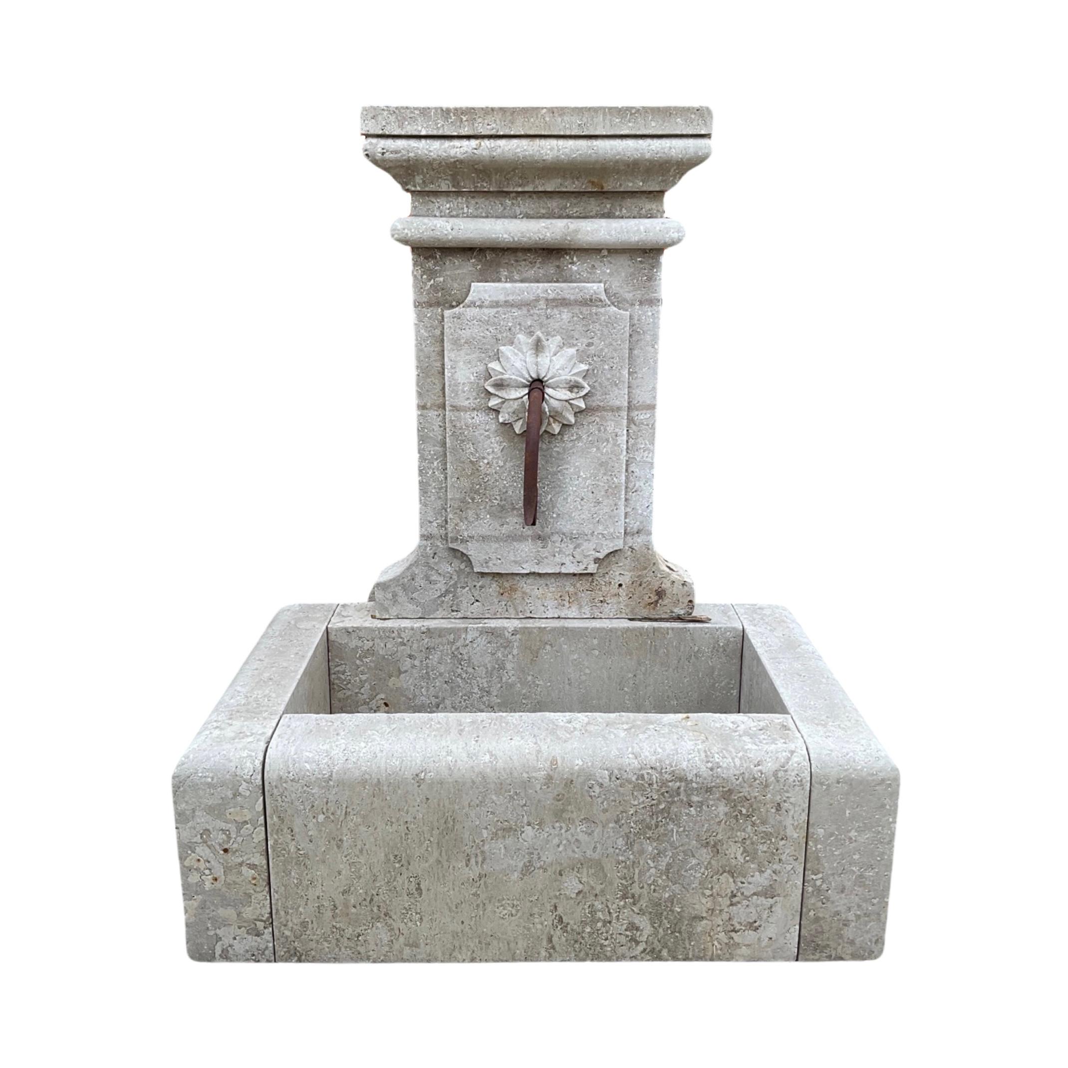 This French limestone wall fountain, originating from the 1960s, features a small rectangular low-line shape basin at the bottom center.  An intricate floral motif at the center top for the water spout exit. Comes with one water spout. The perfect