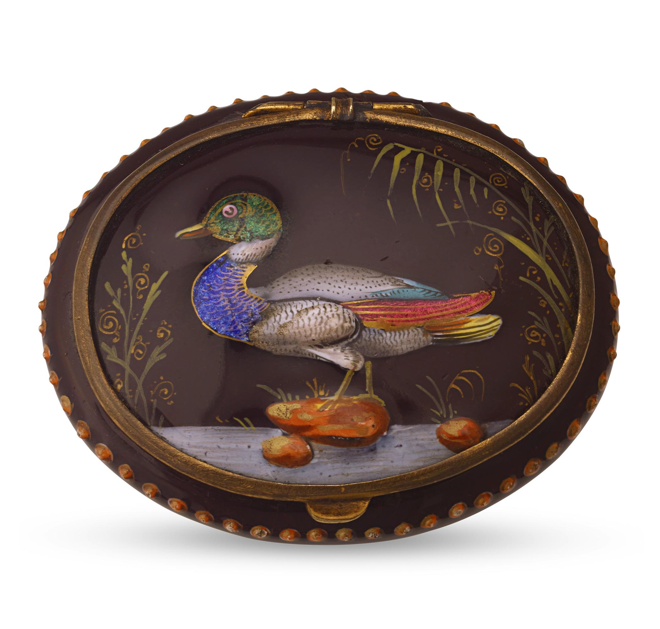 This delightful porcelain and enamel box perfectly exemplifies the esteemed French Limoges tradition. It features a meticulously hand-applied pink and blue floral scene against a brown background. The lid is adorned with gold paint and showcases a