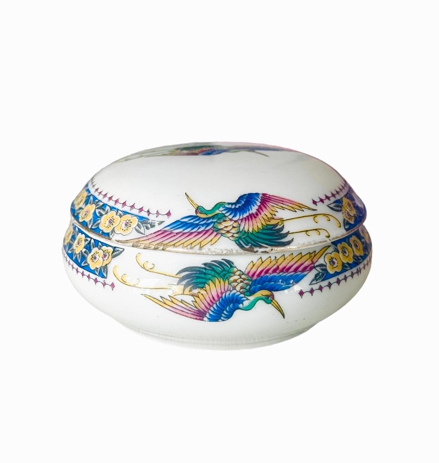 Très jolie et ancienne boîte ou bonbonnière avec couvercle en porcelaine de Limoges à décor d'oiseaux multicolores. Les oiseaux représentés sont des paons. Les bords du couvercle et de la boîte sont décorés d'une frise de fleurs bleues.
Le couvercle