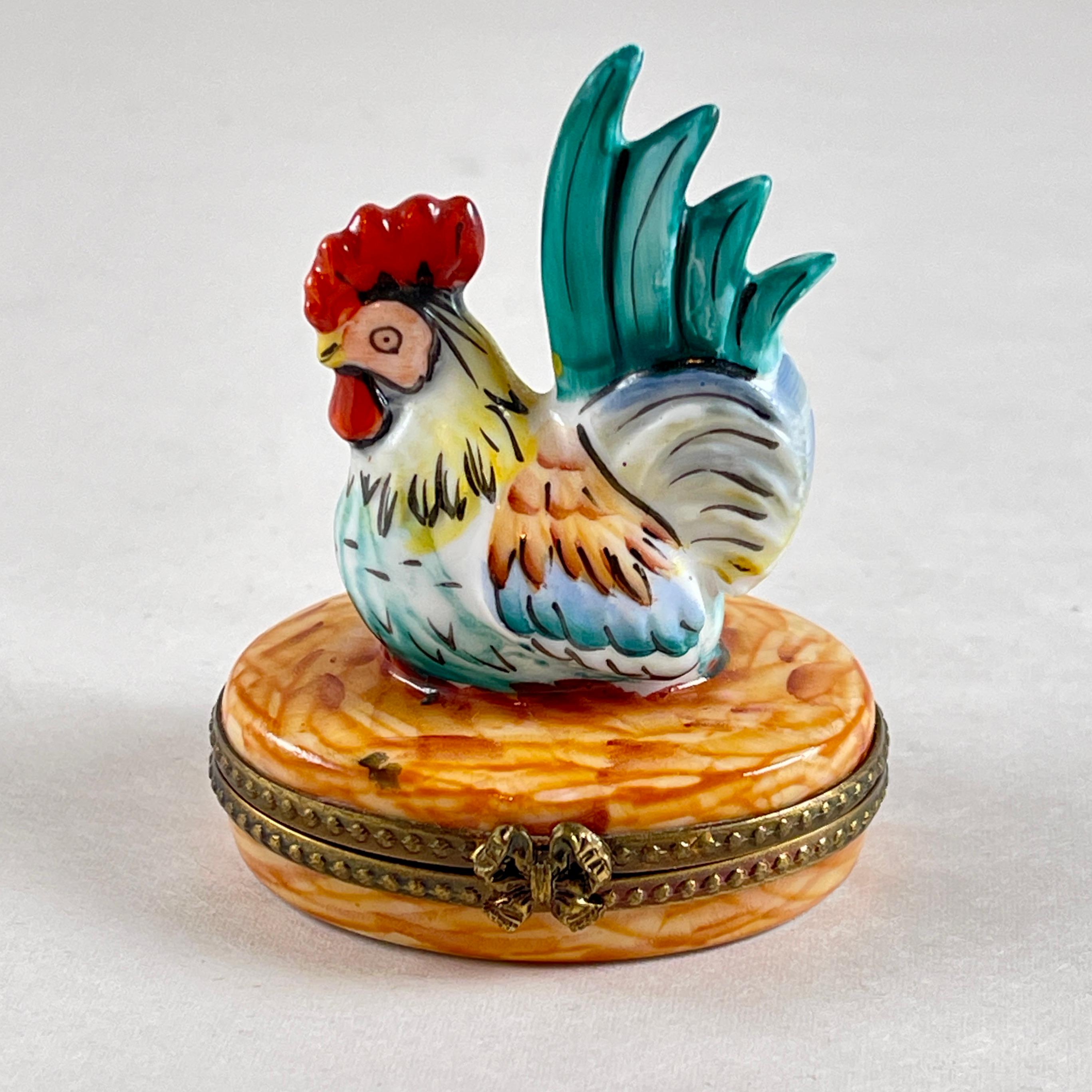 Caja de porcelana francesa de Limoges pintada a mano, un Gallo, hacia la década de 1980.

Un gallo encantador, símbolo de Francia desde la antigüedad, pintado en redondo y sentado sobre un fondo marrón. 

La caja está reforzada en metal dorado con