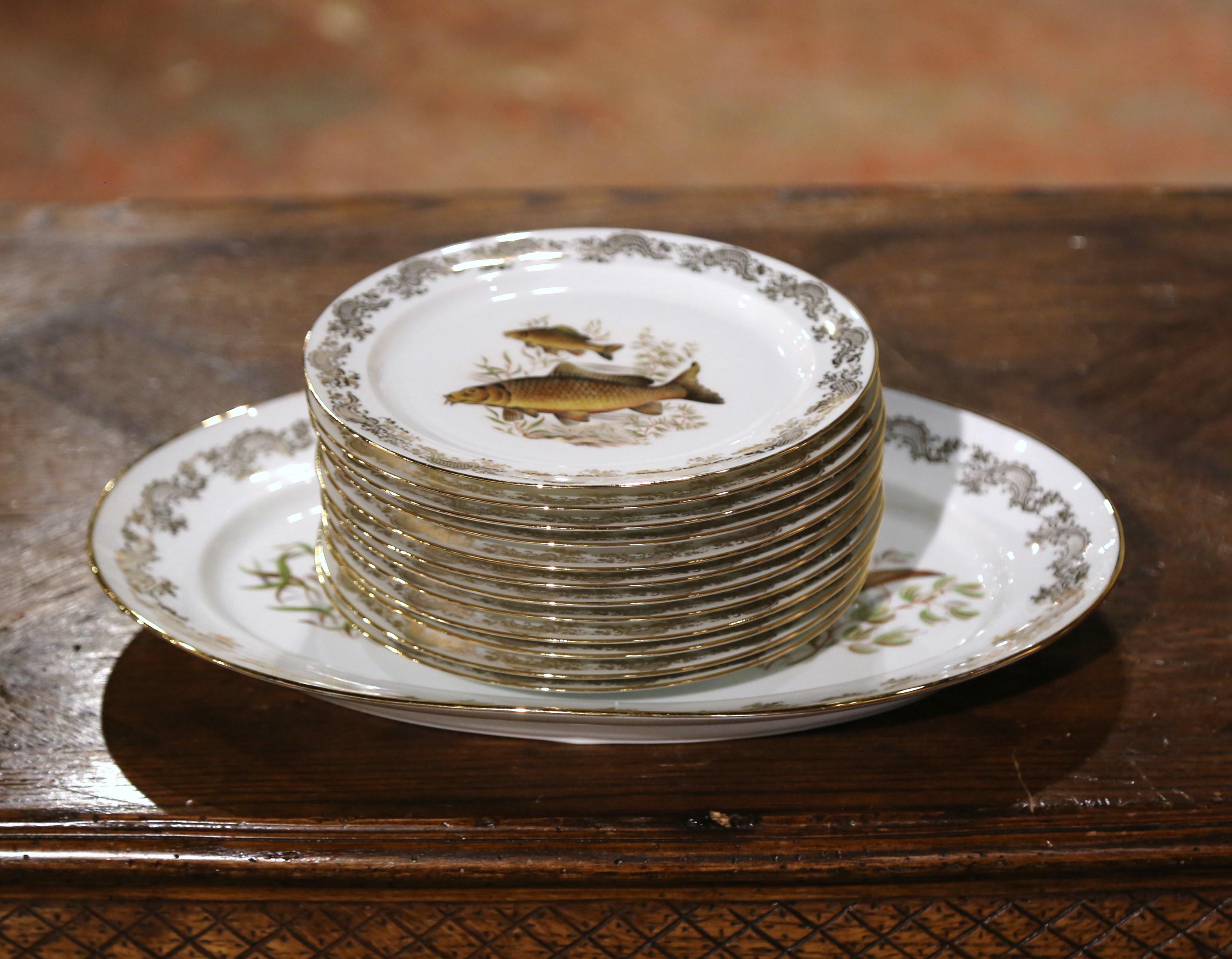 Decorate a vaisselier or a shelf with this colorful set of twelve (12) porcelain plates and matching platter. Crafted in Limoges France, and signed underfoot by the artist, Benoit, each piece is decorated with gilt floral lace border, and features