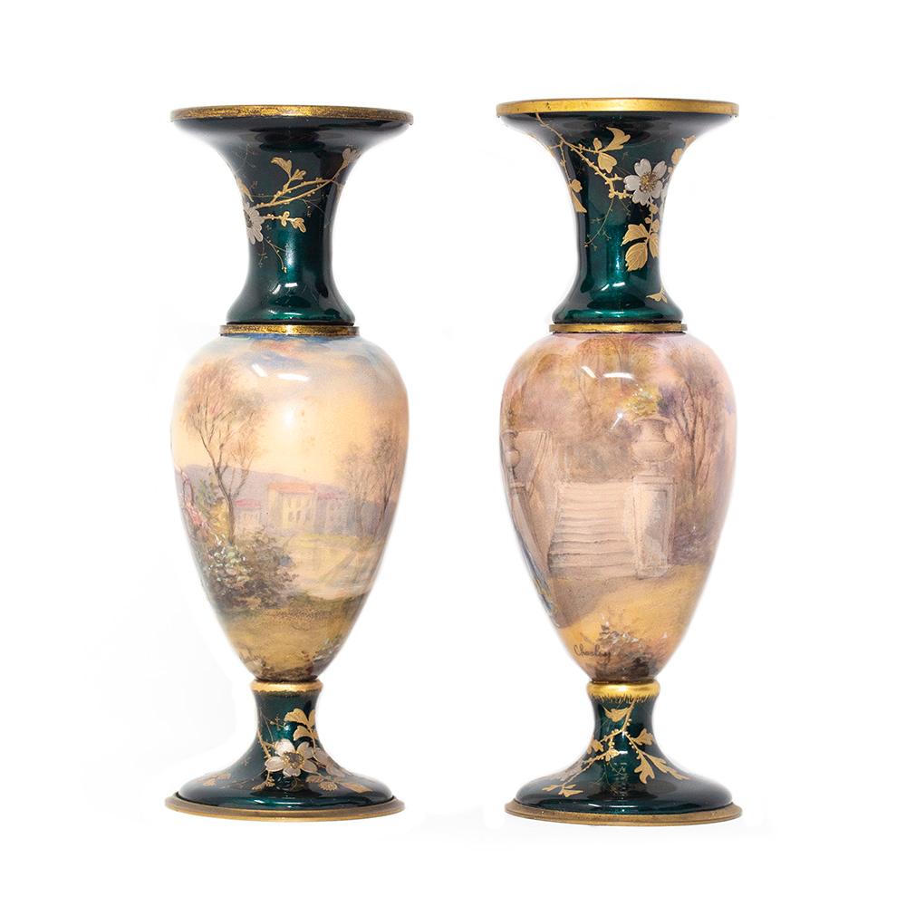 Fine pair of late 19th century French limoge style enamel opposing vases. Each vase with a central female figure in 18th century dress amongst a vast floral landscape with buildings in the background. The top and bottoms with a striking green enamel