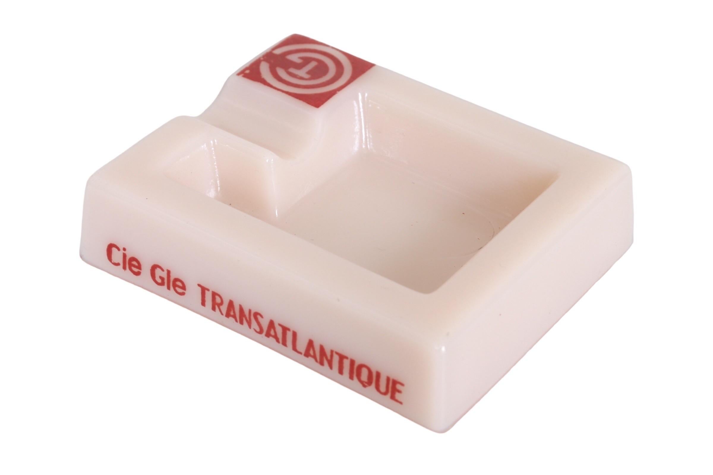 A French Line branded rectangular ashtray by French shipping company Compagnie Générale Transatlantique, known overseas as the French Line. Made of blush colored opalex with a single beveled cigarette rest on the right above the company’s logo; a T