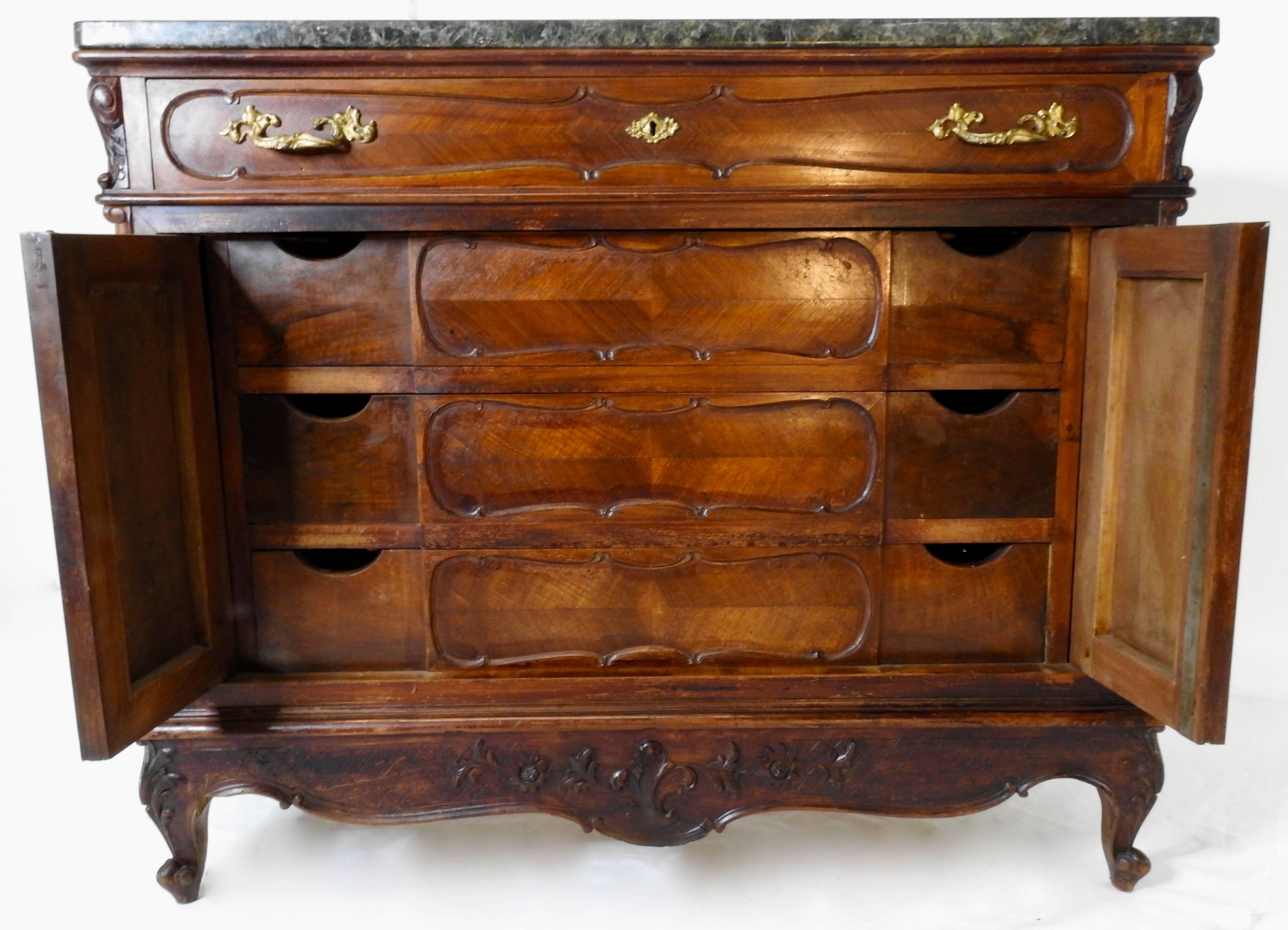 A scalloped apron graces the front of this French linen press featuring a black granite top. One drawer on the top level with the side doors opening to reveal many drawers with dove tails. Feet are of the escargot style.
