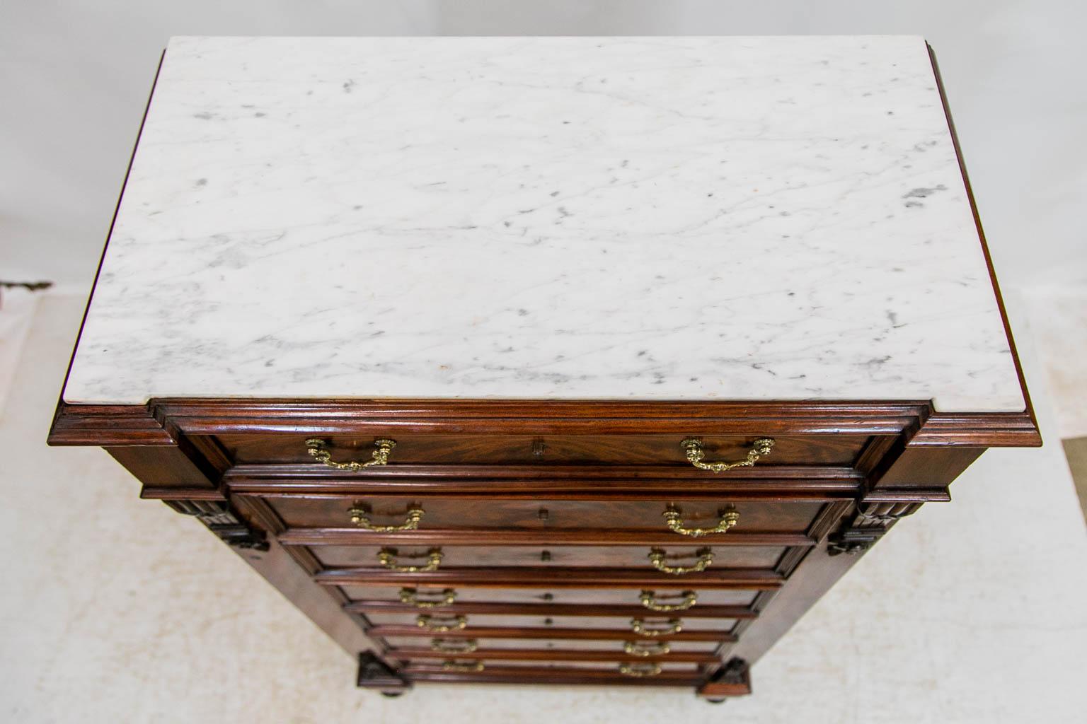 This mahogany lingerie chest has a shaped marble top that is white with light gray veining. The seven drawers have flame grained bookmatched mahogany fronts. All the drawers have working locks with the original keys. The drawers are framed with