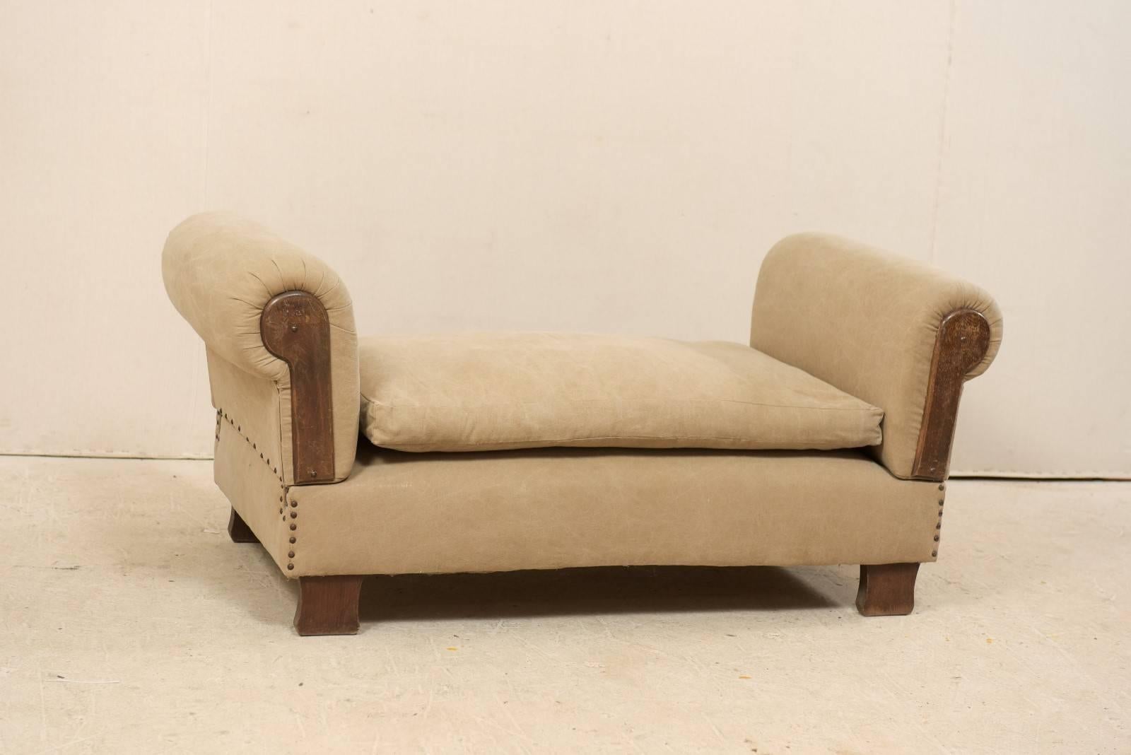 A French lit de jour (daybed) from the 1920s-1930s. This antique French settee features drop style arms on either far end, which when extended converts this bench into a chaise or daybed. The arms have rounded pleating with insert wood panels. This