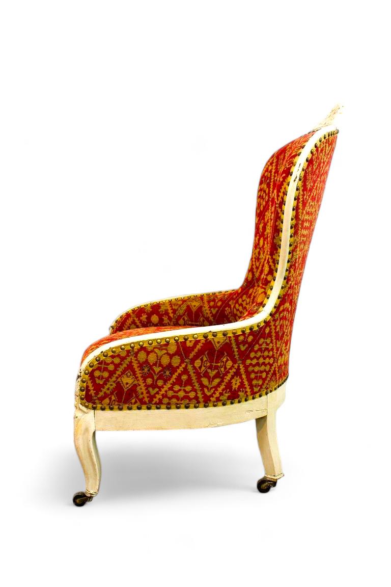 Très élégant fauteuil de style Louis XV tapissé de rouge et de jaune avec des motifs géométriques rappelant des plantes. La base est incurvée et repose sur des roulettes pour faciliter le déplacement. La ceinture de sécurité est sculptée de motifs