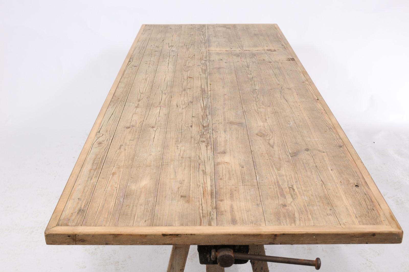 A French, rustic long table with a work-bench base from the early 20th century with rectangular top, splayed legs and cross stretcher. Long ago, this French piece was probably a crunchy work table (an “établi”) but somewhere overtime, a lovely pine