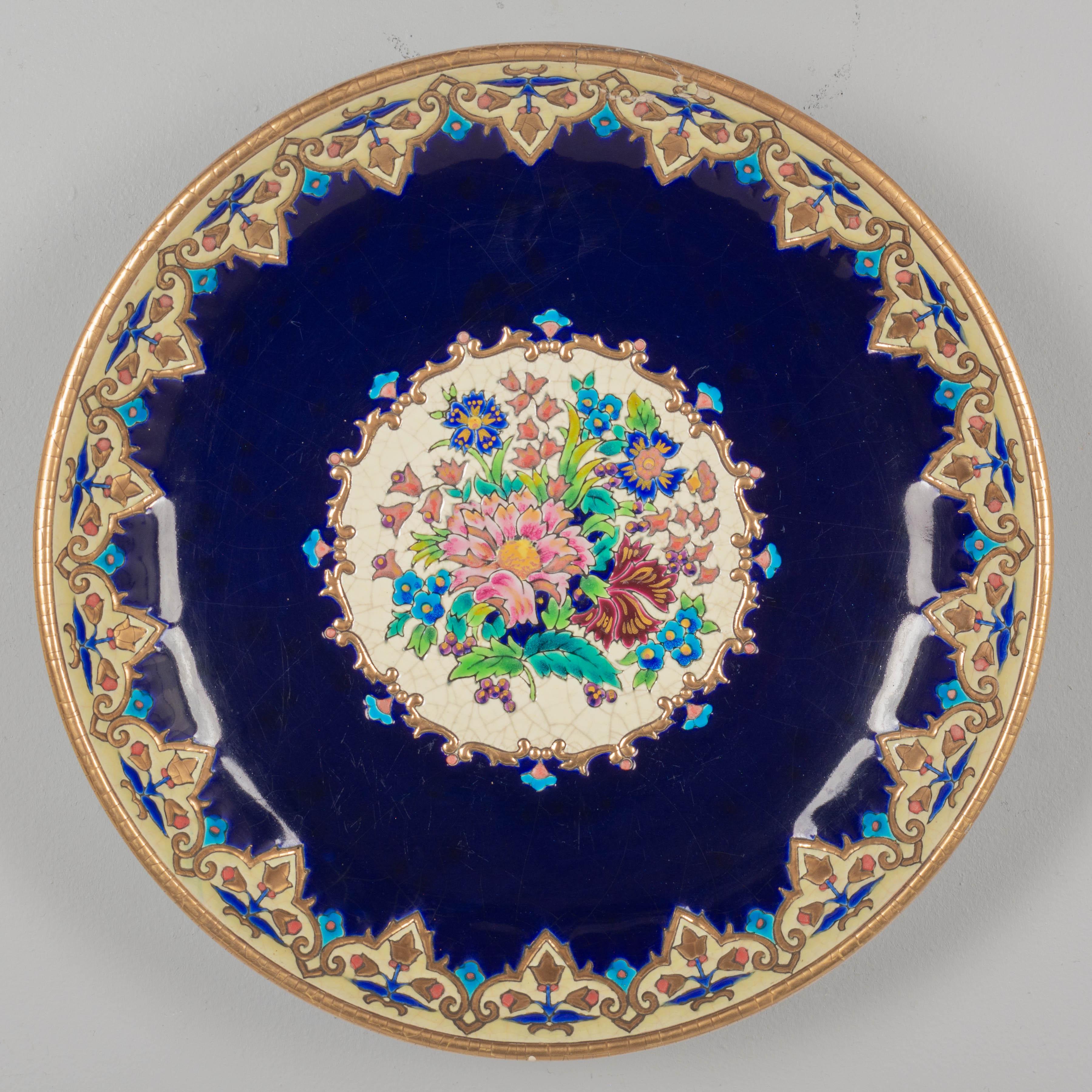Un grand bol centre de table en céramique Longwy de l'Art déco français, peint à la main dans le style de l'émail cloisonné de la Chinoiserie. Fond bleu cobalt foncé avec un bouquet floral central coloré en rose, orange, magenta, vert et bleu. 