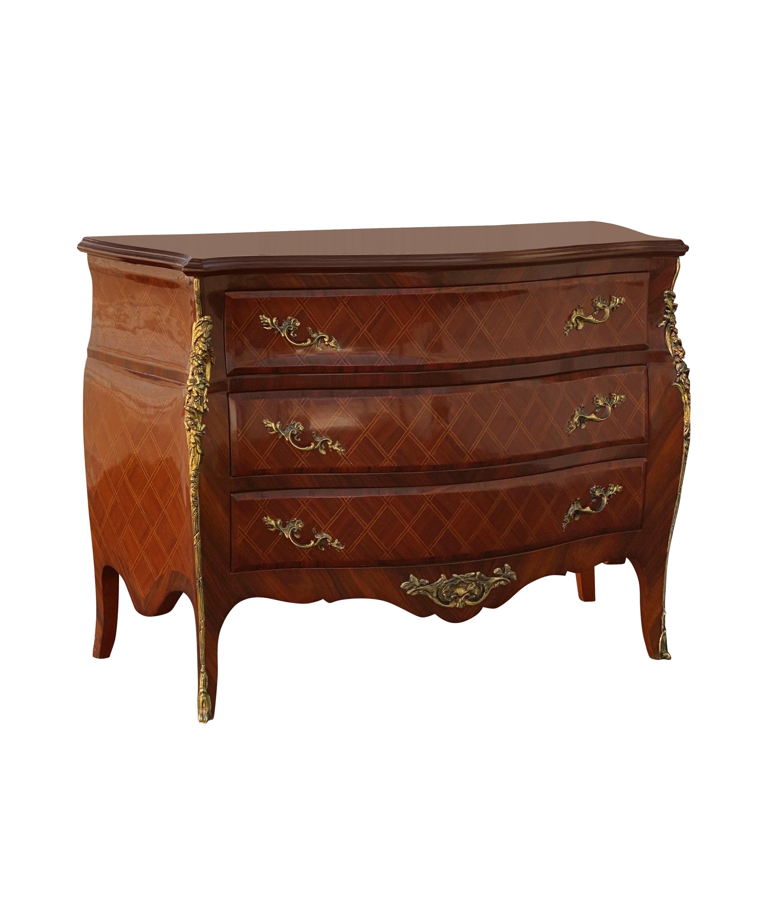 This is a beautiful reproduction piece of a French Louis style antique commode or chest of drawers (or dresser), with a bow bombe shape. Giltwork metal handles and decorations throughout as well as a diamond fretwork inlay design.