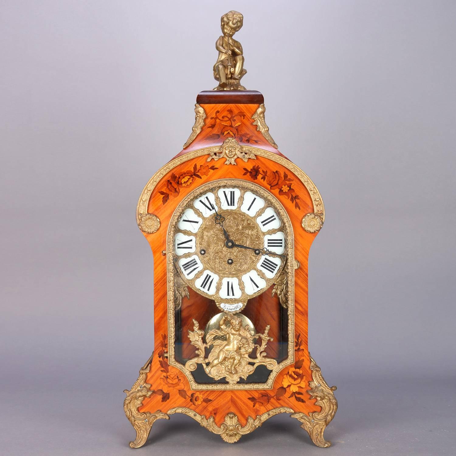 French Louis XIV style bracket clock features bookmatched kingwood case with floral satinwood inlay, figural ormolu cherub, cast foliate and scroll ormolu mounts and Jenny Lind mask, seated on cast acanthus cabriole legs, works marked Germany,