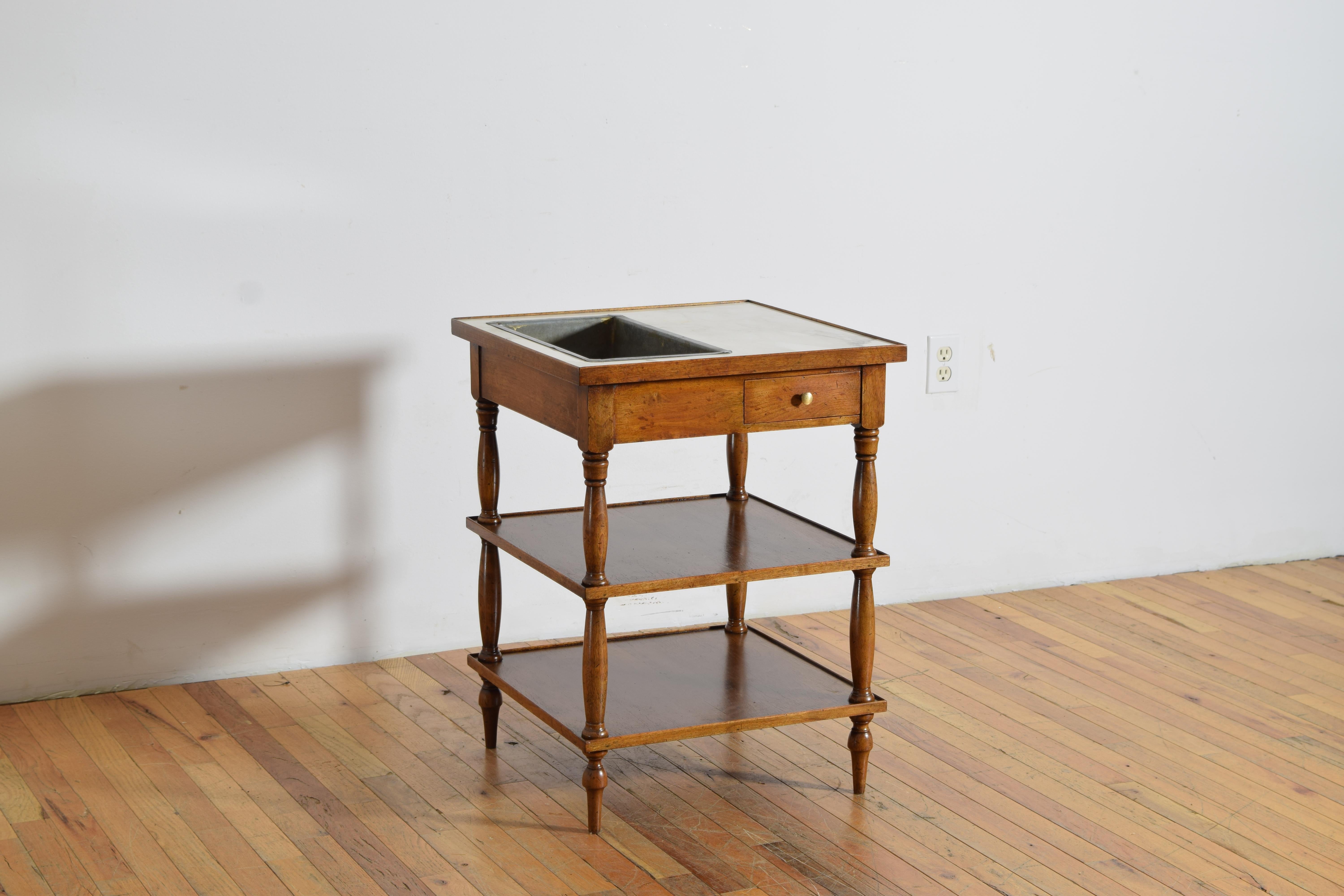 the square top is marble with a zinc ice well used for wine bottles, the top with a raised wooden gallery edge, body of two tiers for accessory and glass storage, raised on turned legs