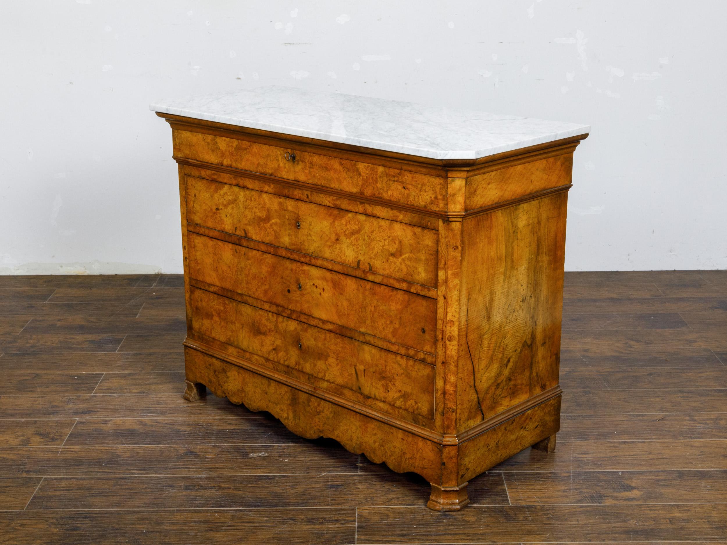 A French Louis-Philippe walnut four-drawer commode from circa 1850 with white marble top and carved apron. This exquisite French Louis-Philippe walnut four-drawer commode from circa 1850 epitomizes refined elegance and masterful craftsmanship.