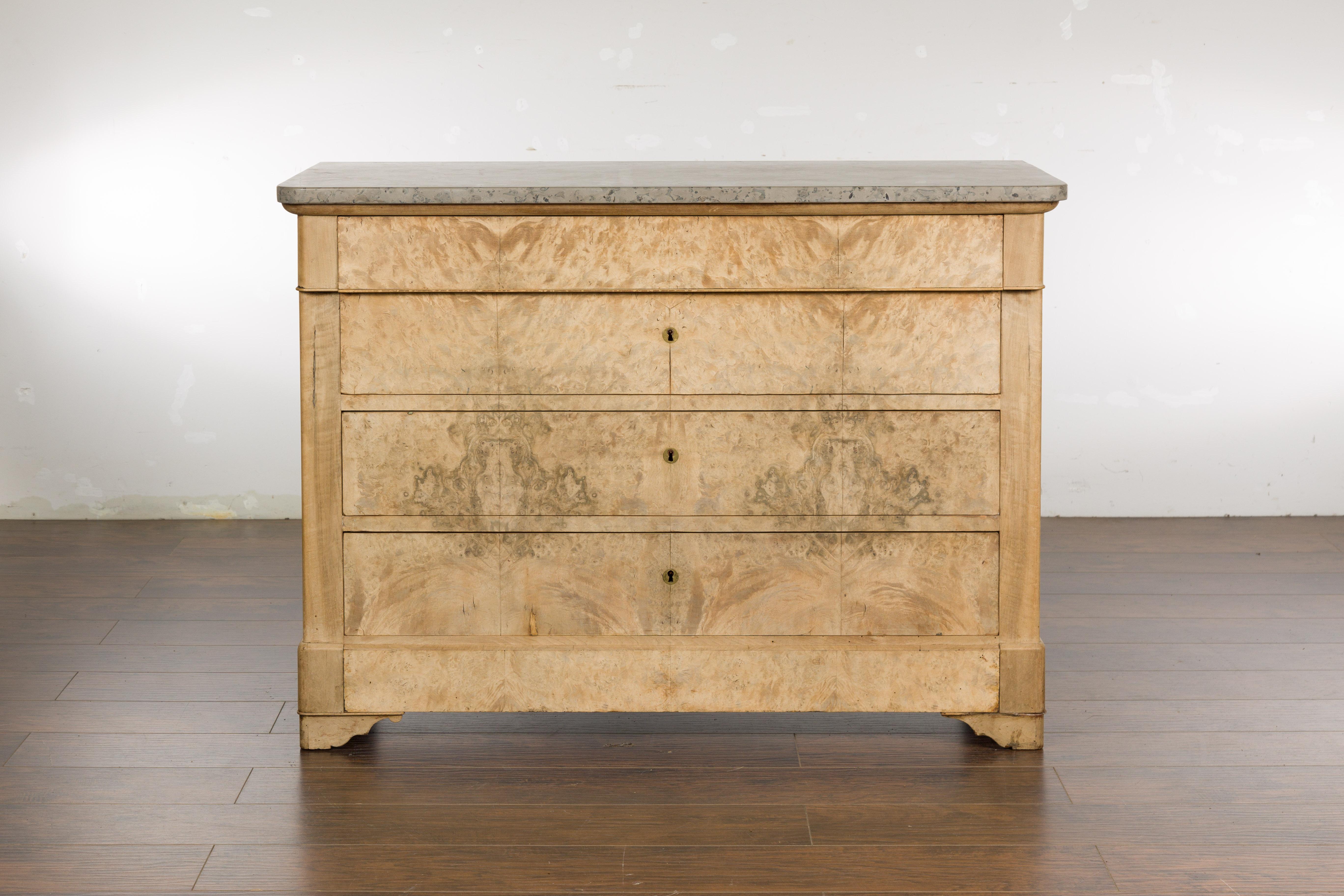 A French Louis-Philippe bleached wood commode from the 19th century with butterfly veneer, marble top and carved bracket feet. Emanating grace and refinement, this French Louis-Philippe bleached wood commode from the 19th century is the epitome of