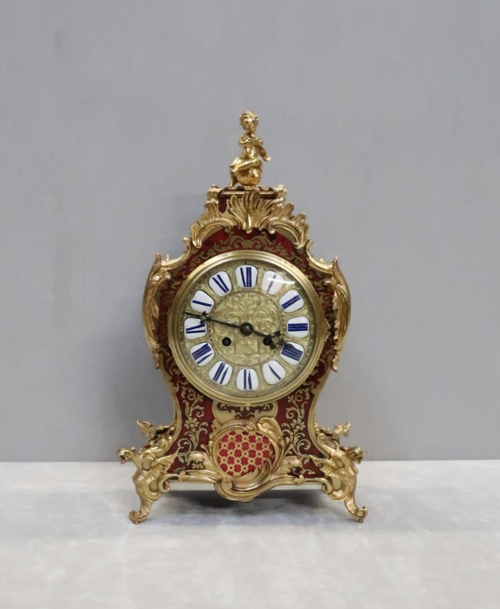 An extremely good quality and impressive French Louis Philippe boulle red tortoise shell and engraved brass inlaid mantel clock with ornate scrolling bronze gilt mounts, fretted brass inset panels and dragons feet finished with cherub to the top The