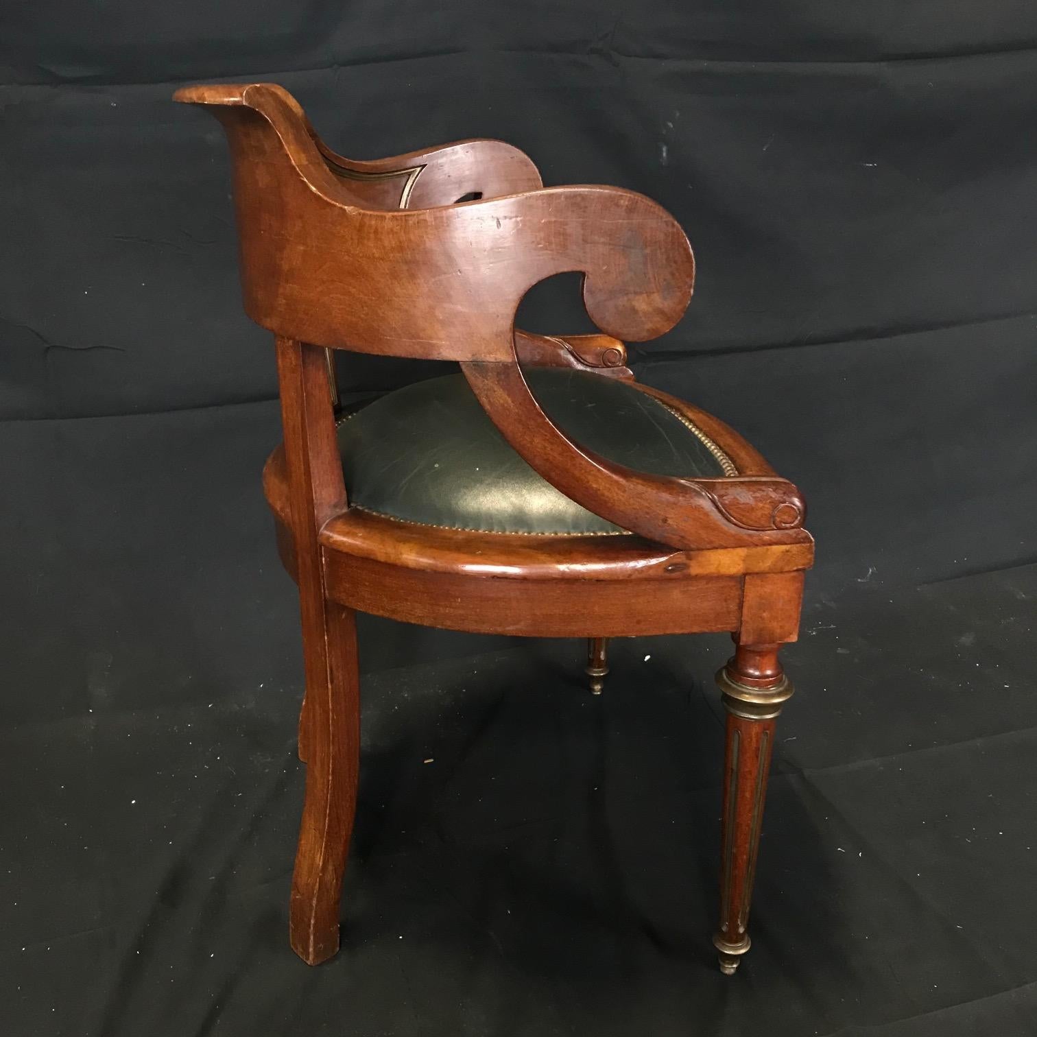 A handsome French Louis Philippe walnut desk chair with rounded back, scroll arms, green leather seat with brass studded border ending in reeded tapered turned legs. 
 
#3804
Measures: H seat 18”, H arm 29”, D 20”.