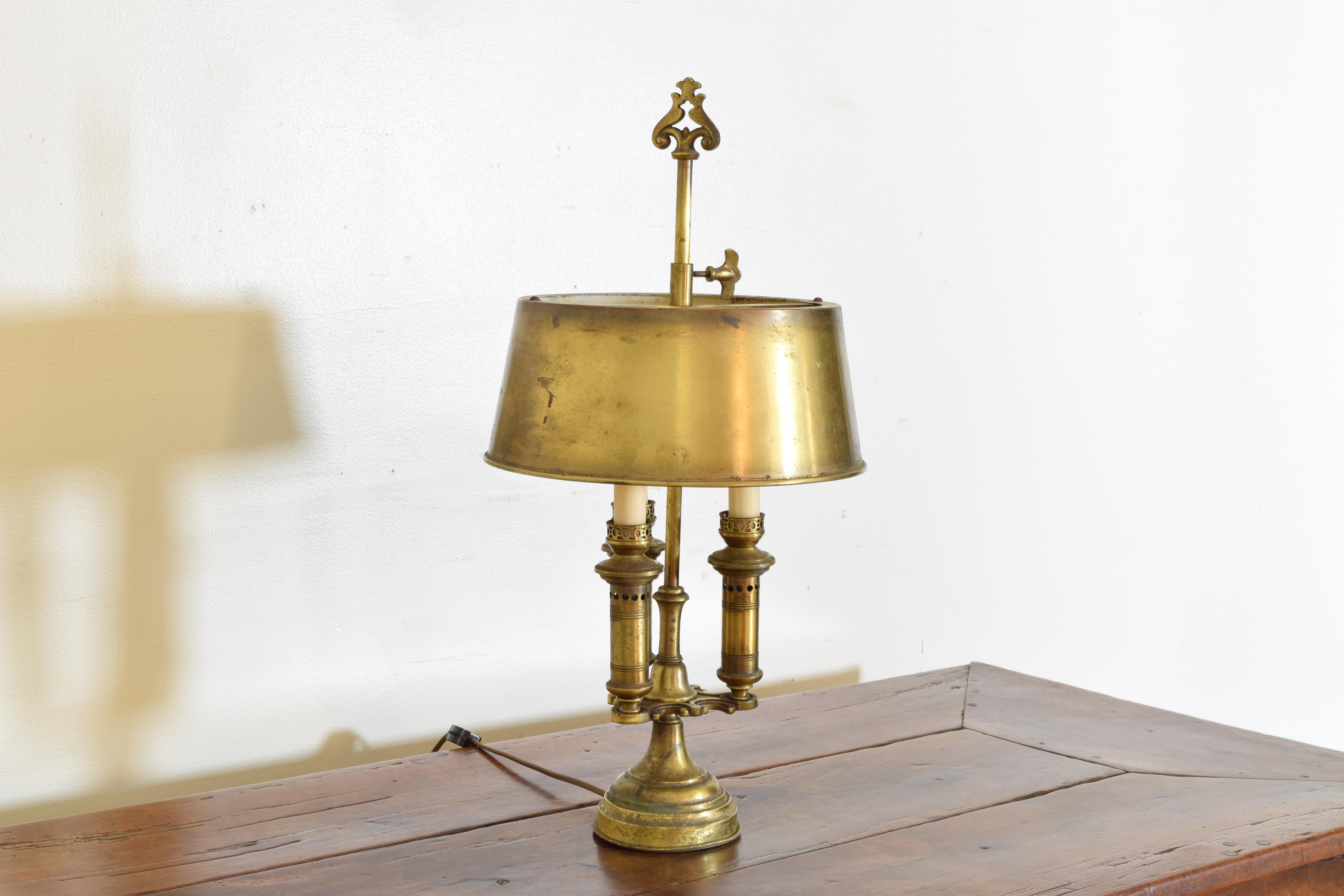 Having it’s original and adjustable brass shade this exceptional and thoughtfully detailed lamp features a central standard and a mid-base issuing three cylindrical pierced candleholders, raised on a shaped pedestal base, originally made for