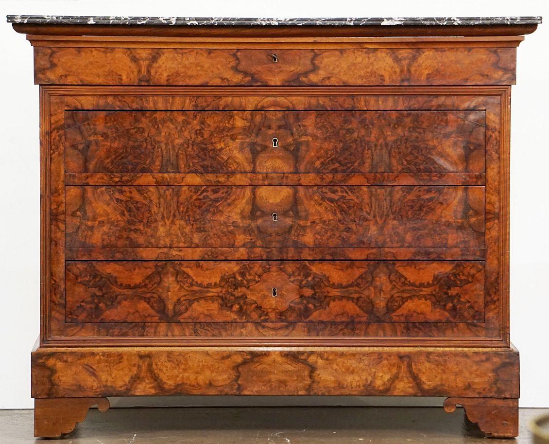 A handsome Louis Philippe console chest or commode from France, of beautifully patinated burled walnut with a figured marble top, featuring four fitted long drawers, brass escutcheons, and set upon shaped feet.