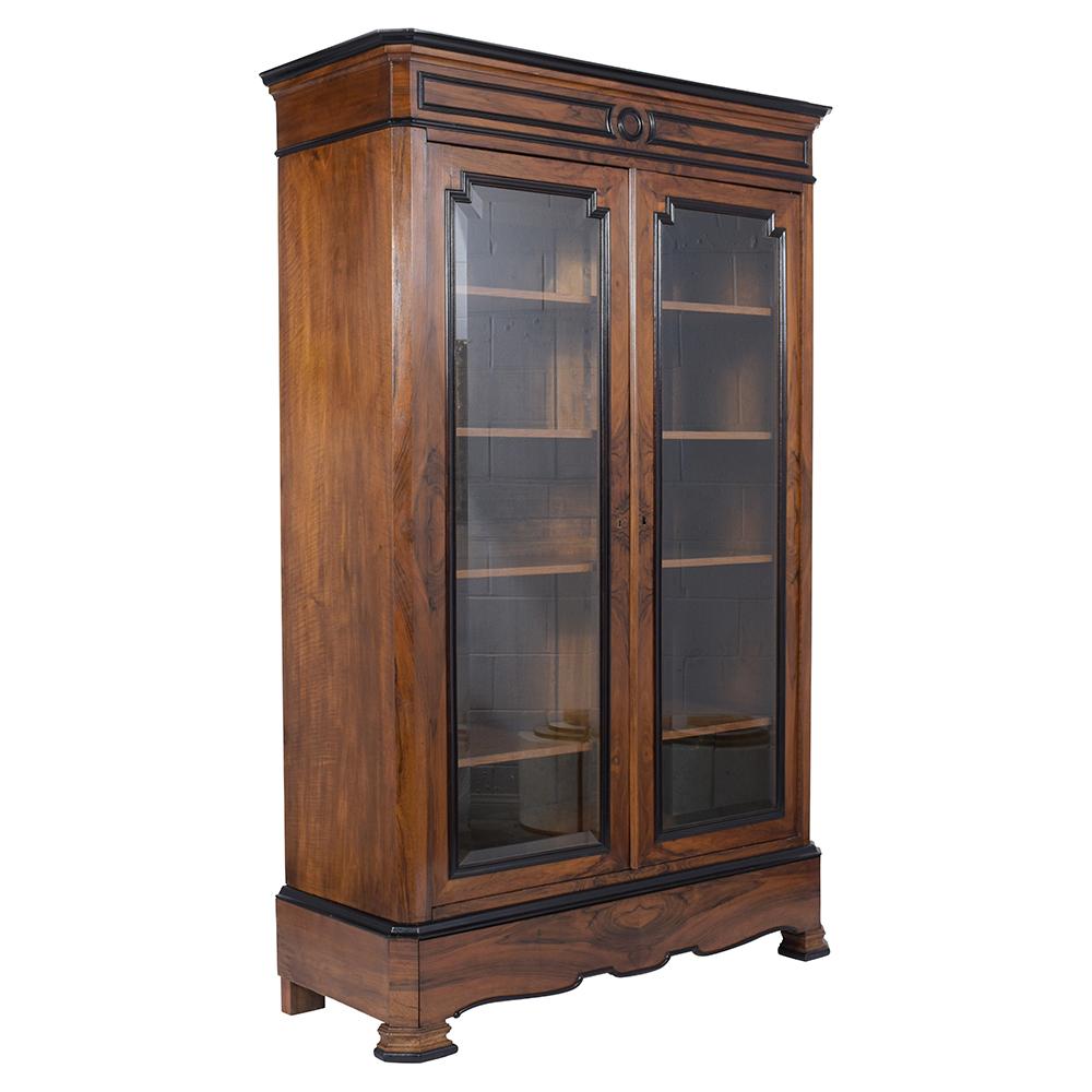 This Extraordinary French Louis Philippe Bookcase is handcrafted from solid walnut wood and features its original walnut finish with an elegant ebonized molding accents details. This antique display comes with double framed doors with original clear