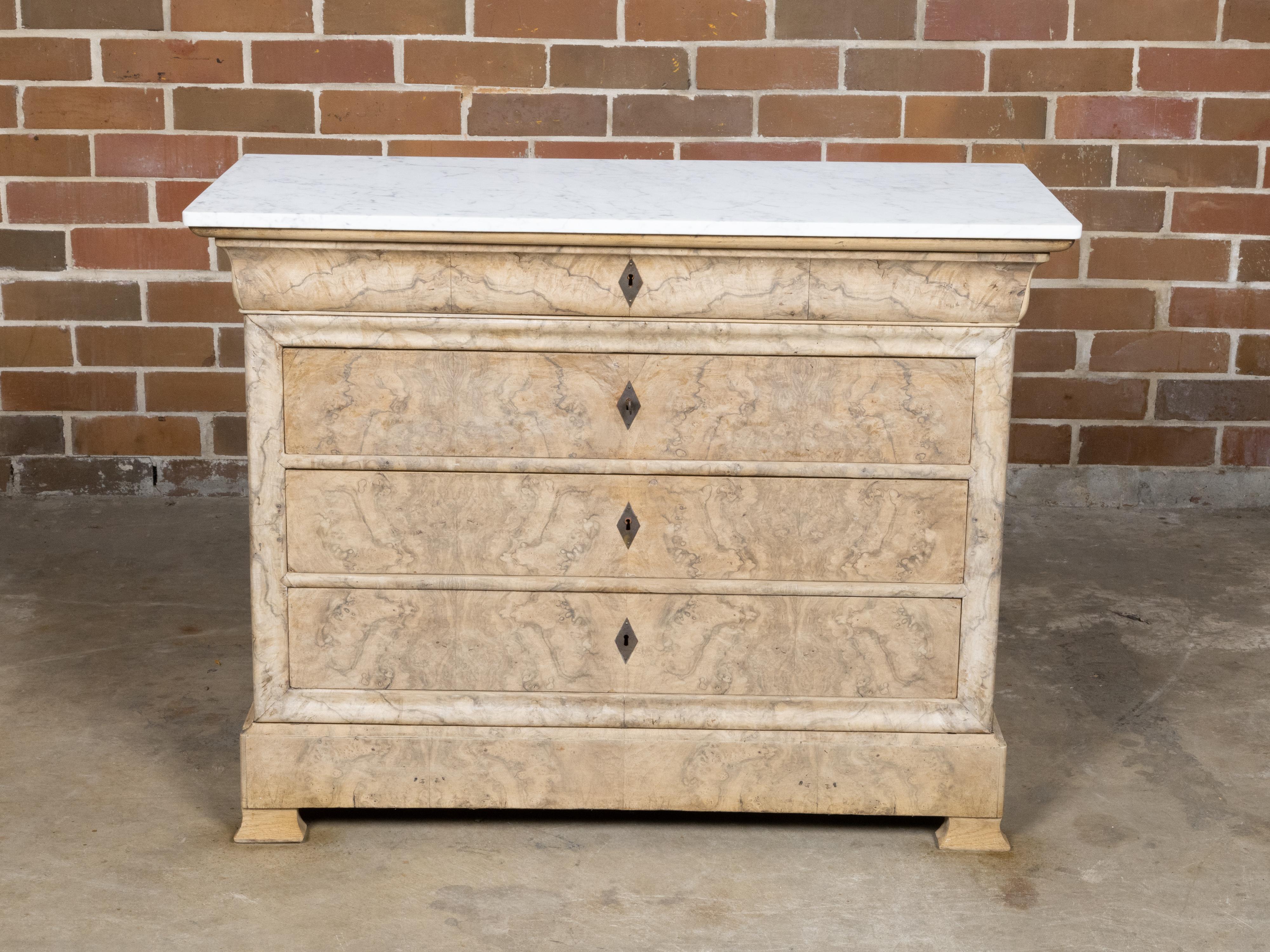 A French Louis-Philippe bleached wood commode from the 19th century with bookmatched veneer, white marble top and four drawers. This French Louis-Philippe bleached wood commode from the 19th century exudes a subtle elegance and refined taste, making