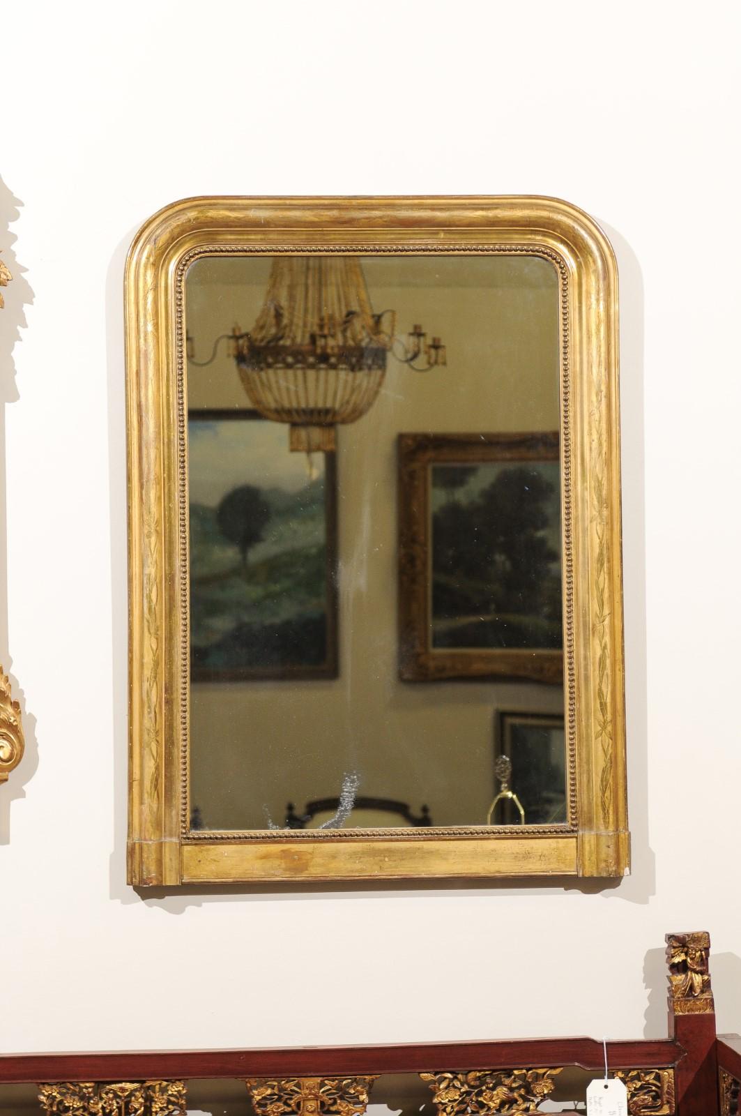 A classic Louis Philippe gold leaf mirror characterized by its curved top corners and simple rectangular base. Adjacent to the mirror glass is a row of beading. Decorative etching also is on the frame. Due to the glass being original there is some