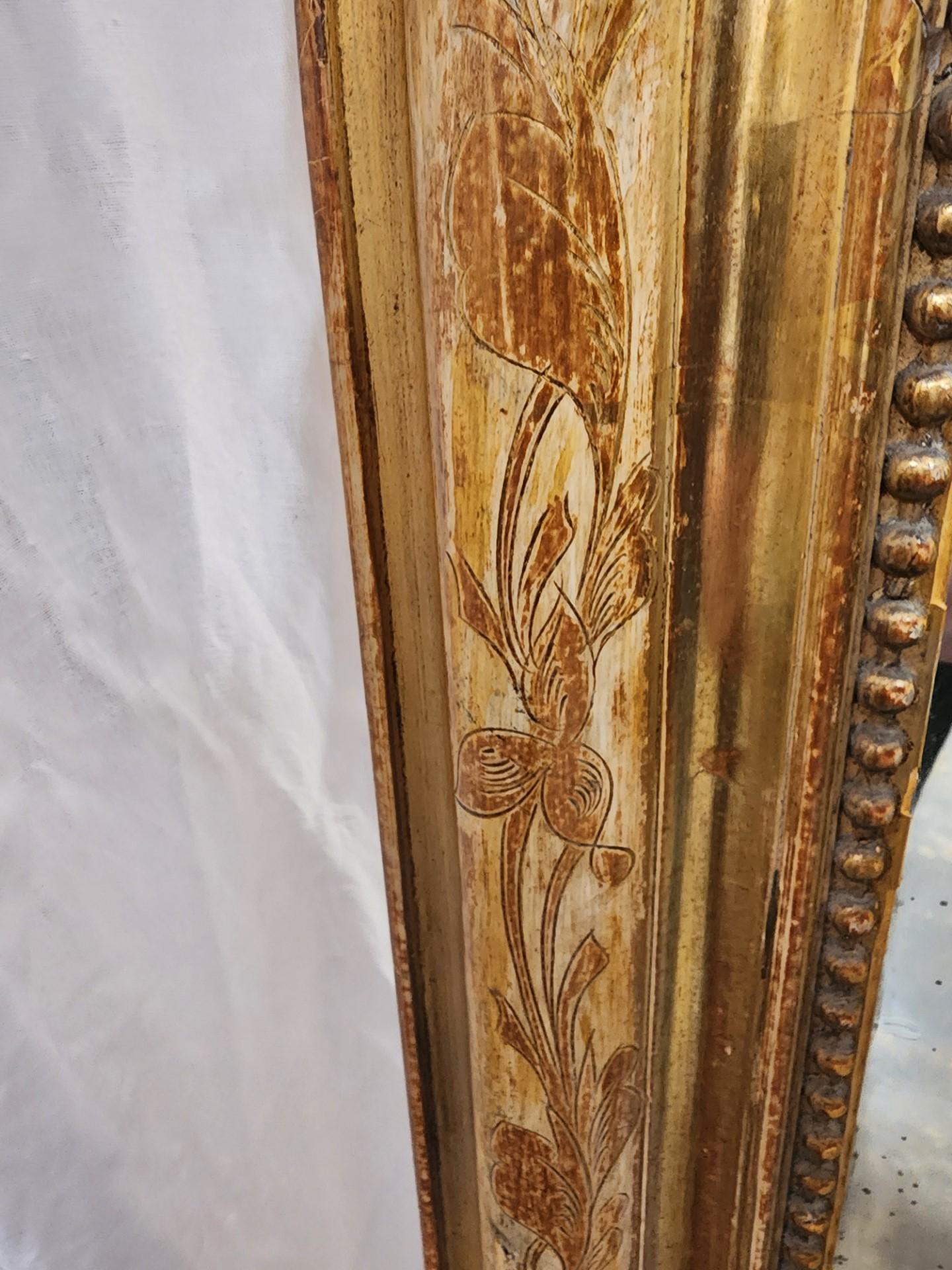 French Louis Philippe period giltwood wall mirror, mid 19th c., having arched frame with incised foliates and beaded trim, encasing later flat mirror plate.