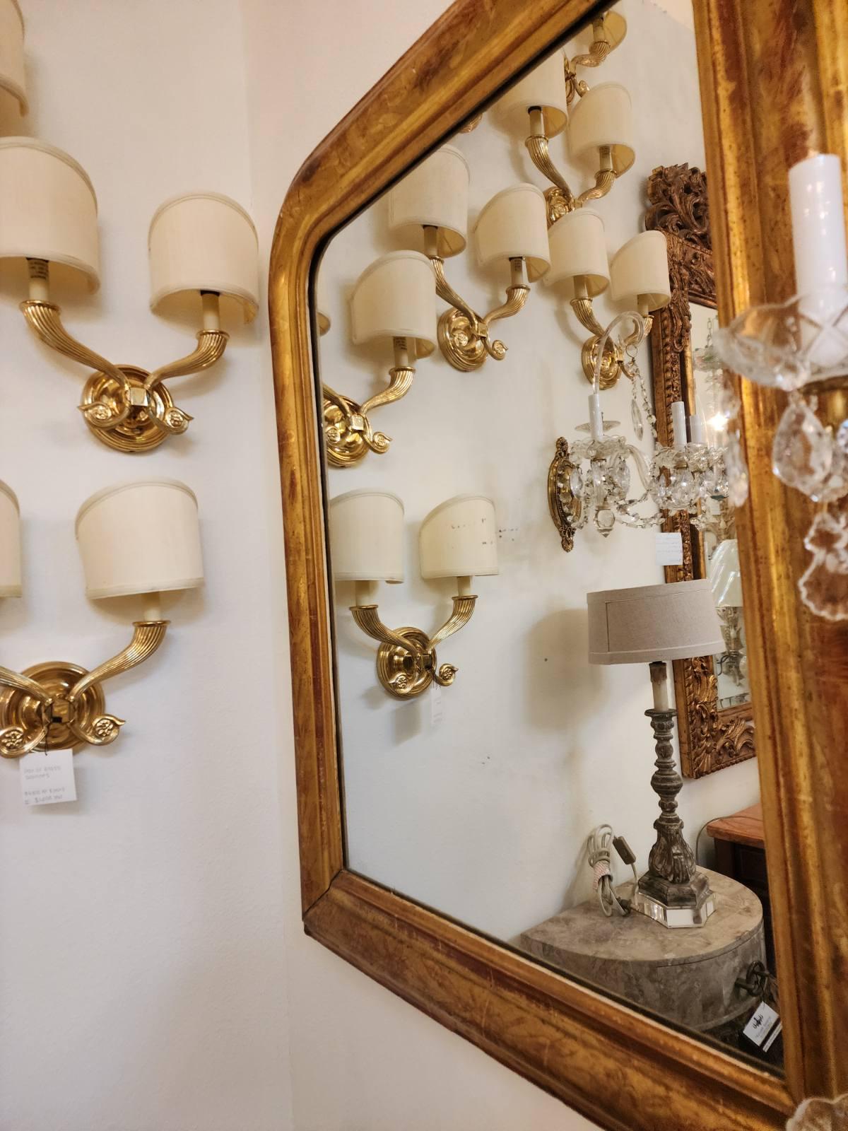 This French Louis Philippe period giltwood wall mirror from the mid-19th century is a stunning piece featuring an arched frame adorned with intricate floral motifs. The elegance of the giltwood accents adds a touch of luxury to the mirror, which