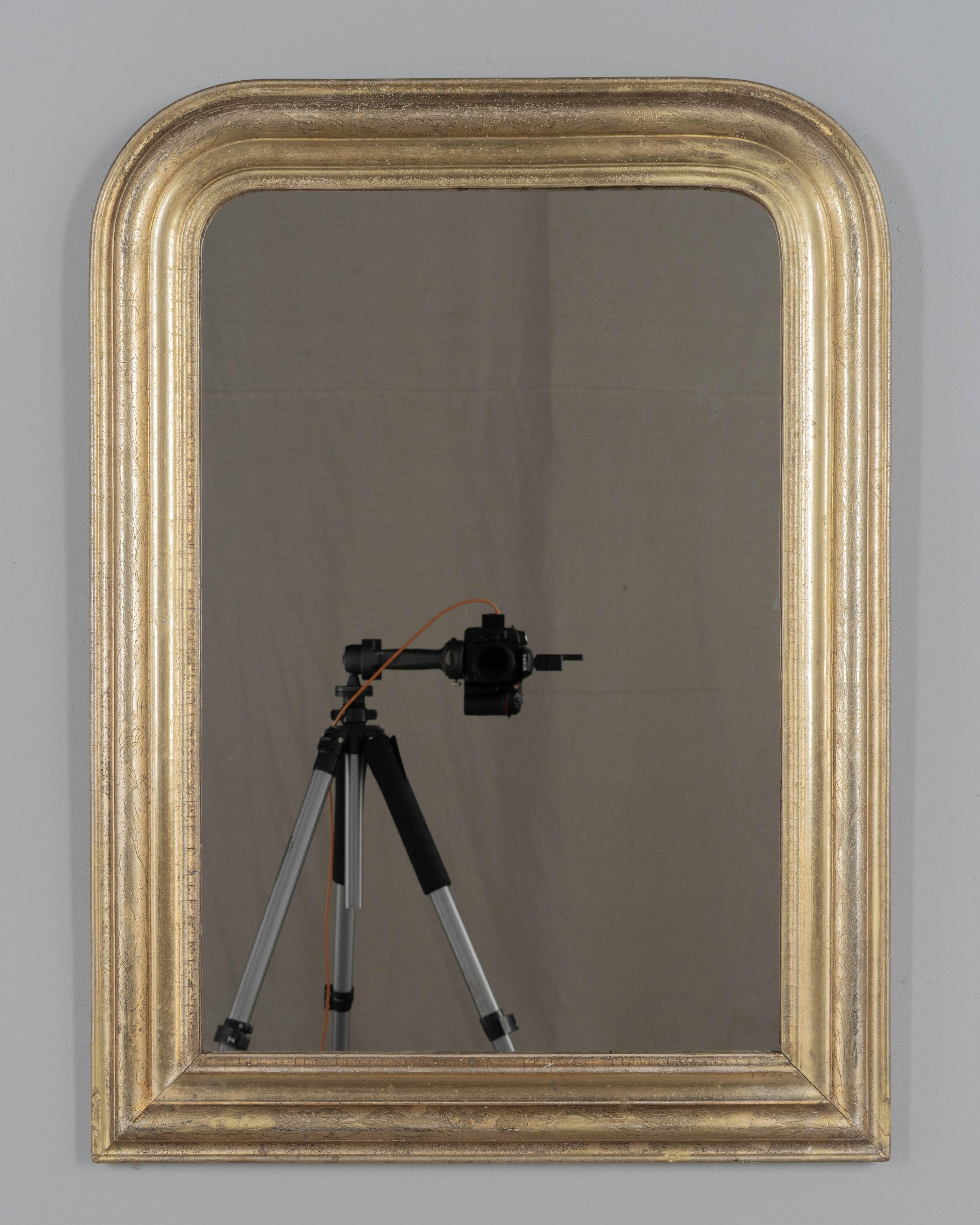 An early 20th century French Louis Philippe style mirror with curved top corners, incised floral decoration and bright gilt finish. New 1/4 