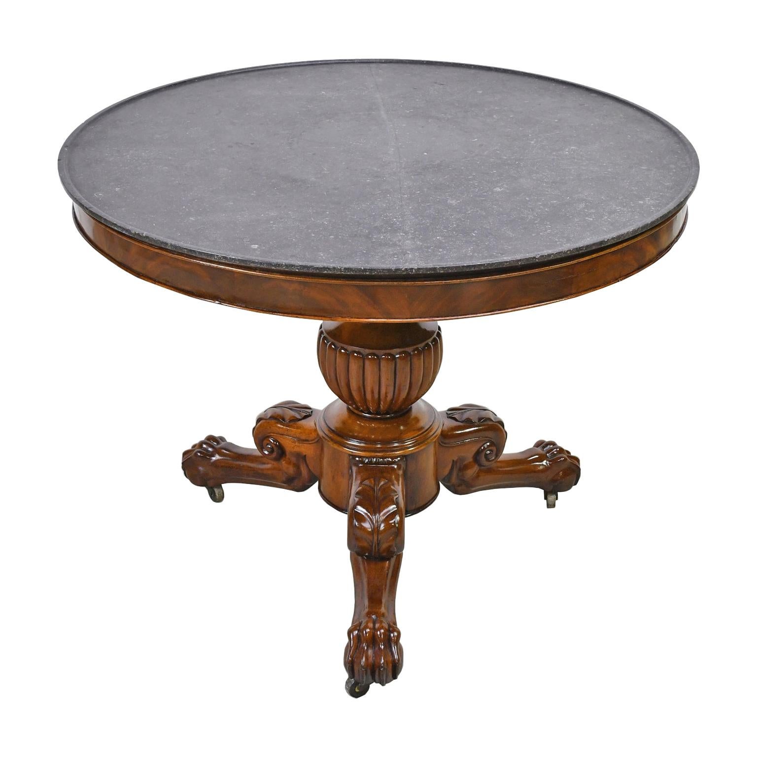 Somewhat larger than usual, this French Charles X guéridon in fine West Indies mahogany has the original round black marble top with a champhered edge that rests on an apron showcasing the figuring of this beautiful wood. The pedestal is composed of