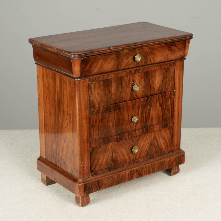 A French Louis Philippe style miniature commode, or sample chest made of beautiful book matched veneer of walnut. Four dovetailed drawers with blue velvet lined interior. Original brass knobs.