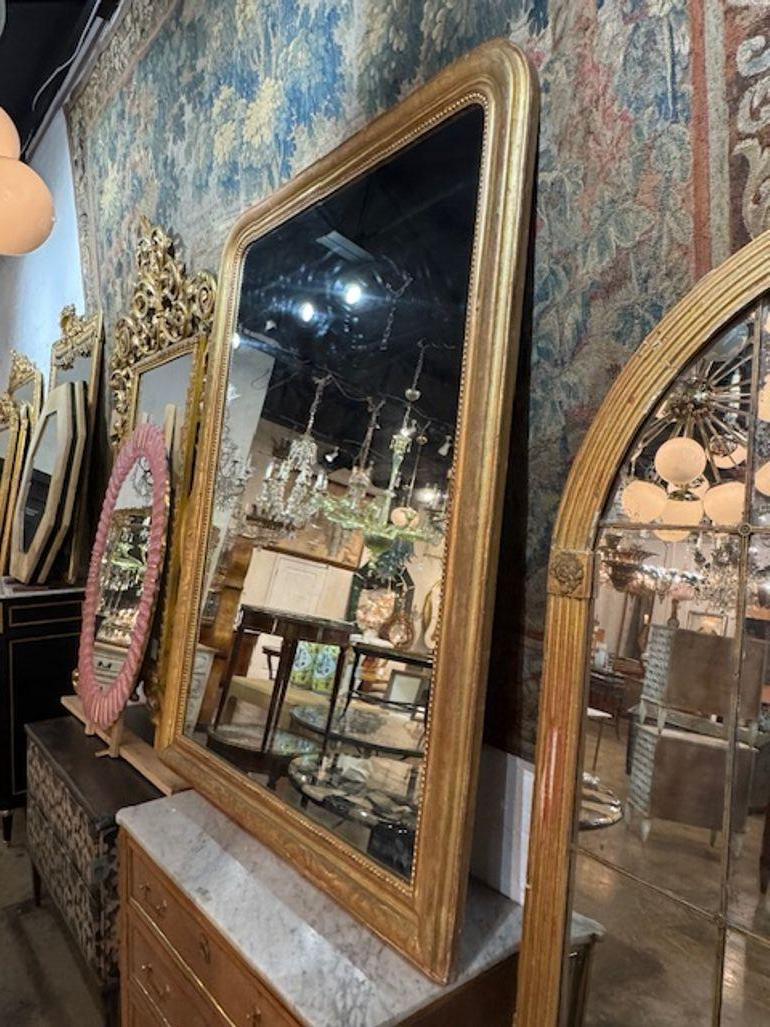 Large 19th century French Louis Philippe giltwood mirror with floral pattern frame. Louis Philippe giltwood mirrors are known for their graceful arched frames, rich gold leaf finishes, and timeless silhouettes. Circa 1860. 53w x 72h 