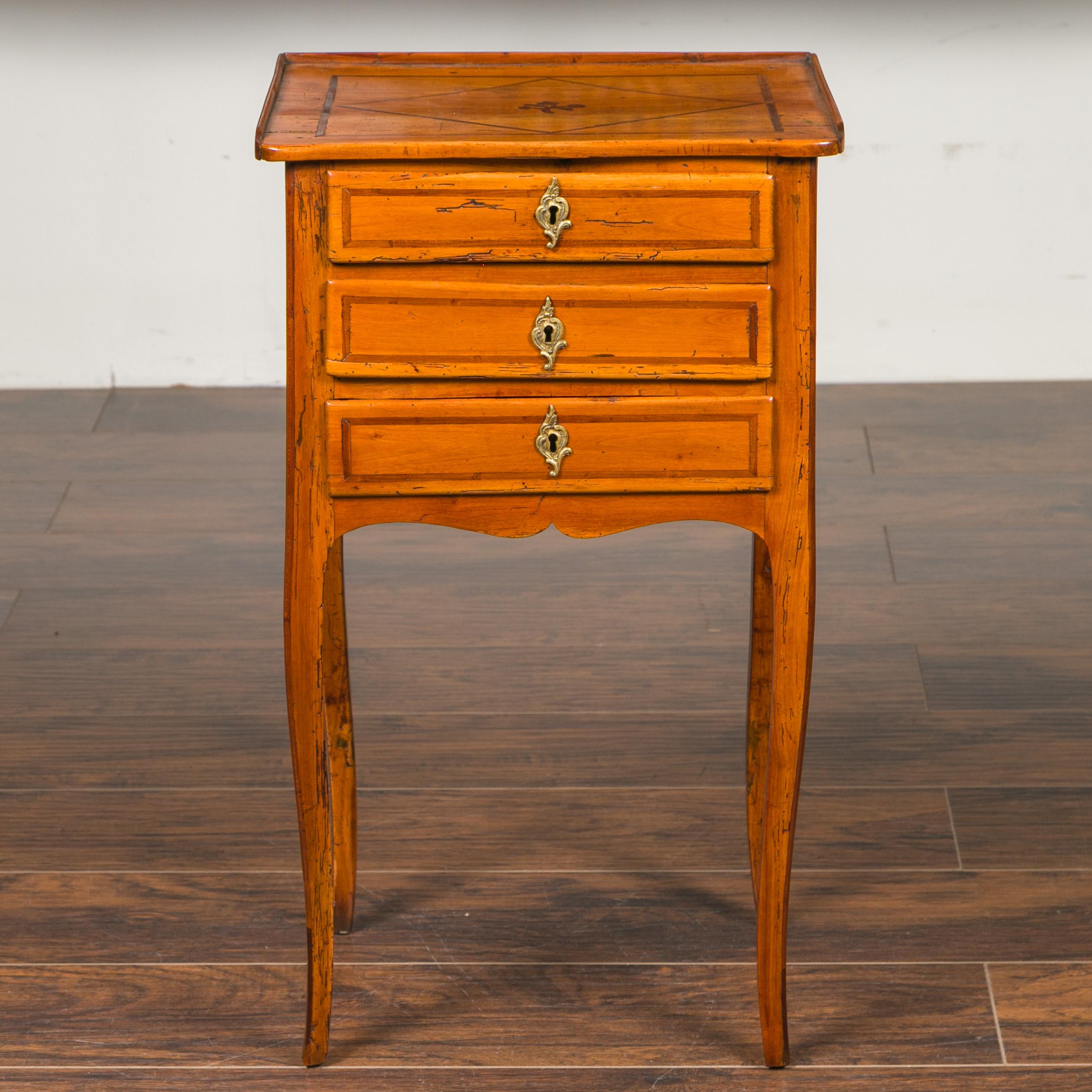A French Louis-Philippe period walnut bedside table from the mid-19th century, with three drawers, banding and diamond motifs. Born in France during the reign of King Louis-Philippe, this walnut side table features a rectangular top with
