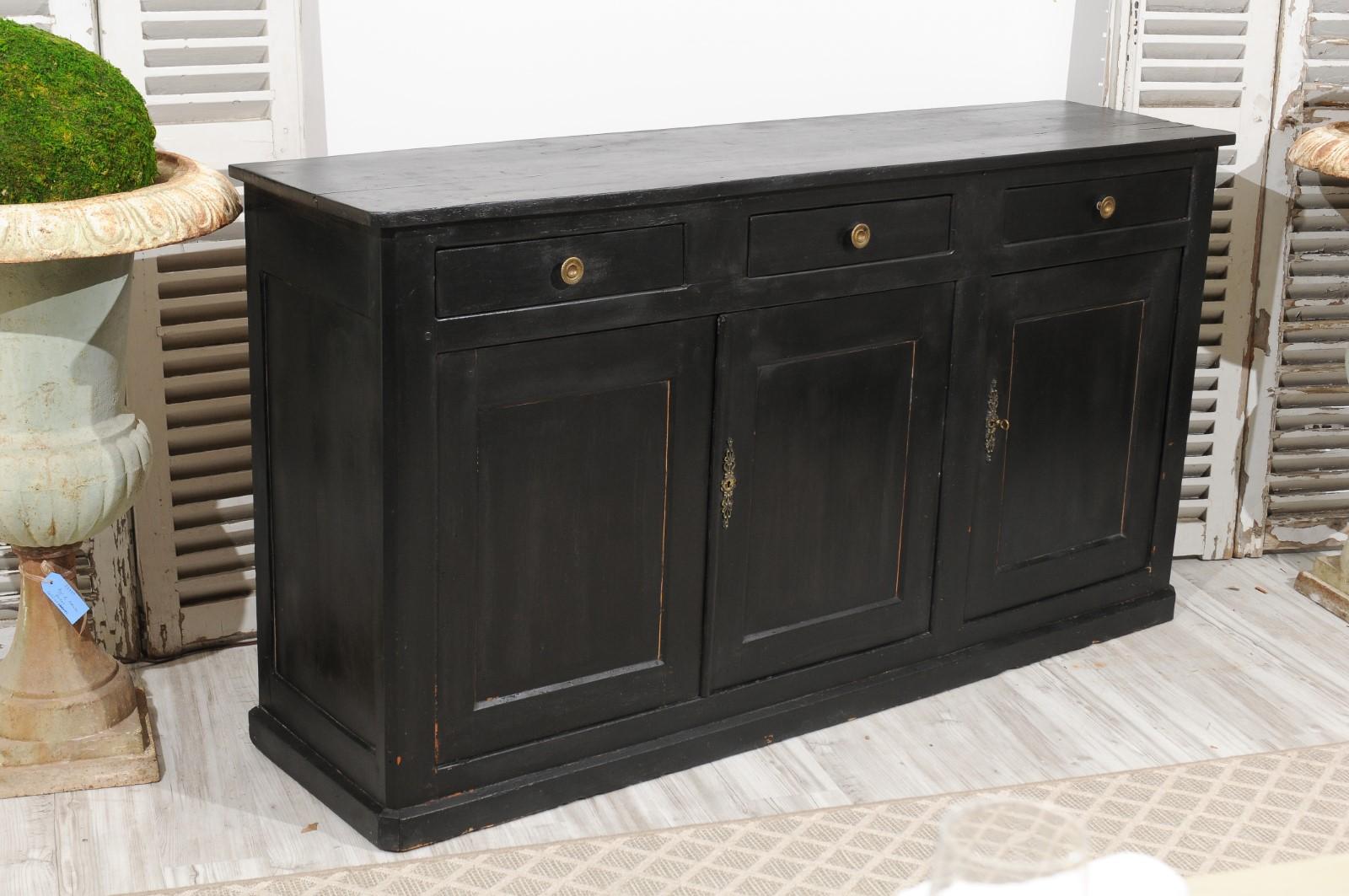 A French Louis-Philippe period black painted walnut enfilade from the mid-19th century, with original brass hardware and three drawers over three doors. Born in France during the reign of France's last king Louis-Philippe, this elegant enfilade