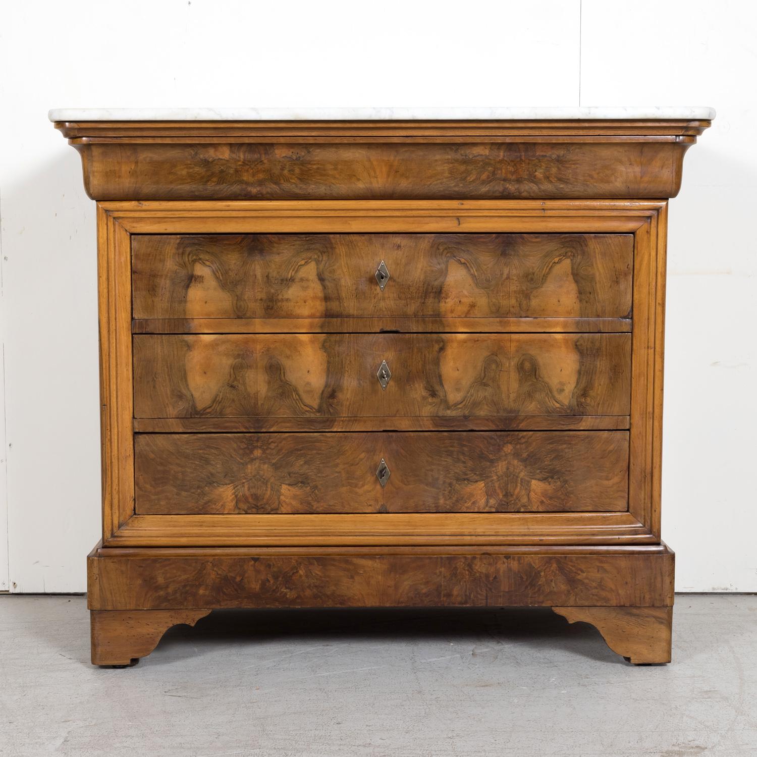 An exceptional 19th century French Louis Philippe period commode handcrafted of walnut by talented artisans in Provence near Avignon, circa 1830s, having the original white Carrara marble top with rounded corners resting above the typical hidden